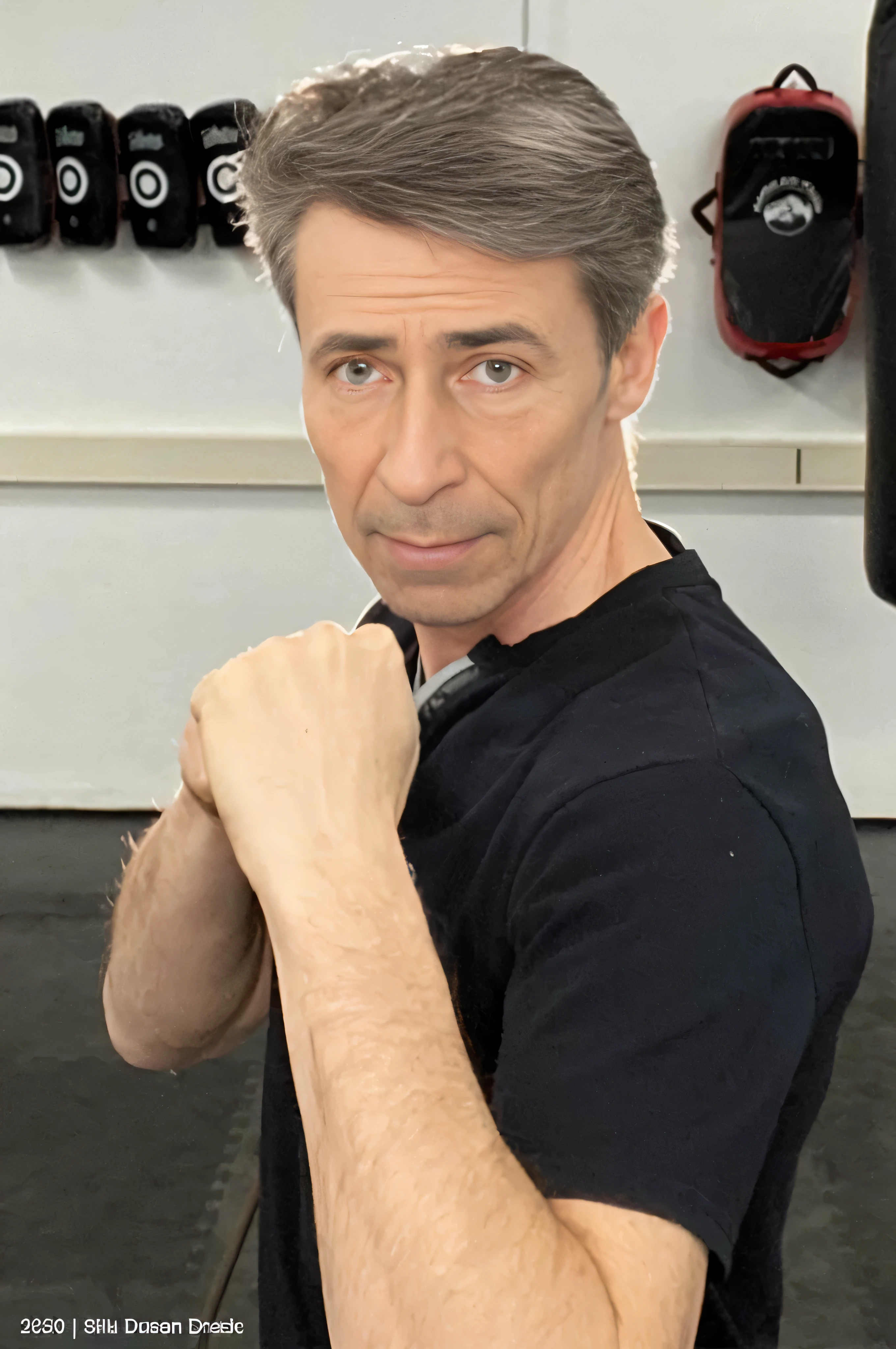 Da ist ein Mann, der mit einem Boxsack in einem Fitnessstudio steht, in a Kampfhaltung, taken in the early 2020s, in Kampfpose, Fighter pose, Michael Pangrazio, Mann in Verteidigungshaltung, Kampfhaltung, posing ready for a fight, George Doutsiopoulos, selbstbewusste Action-Pose, Kampfpose, inspiriert von Ken Kelly