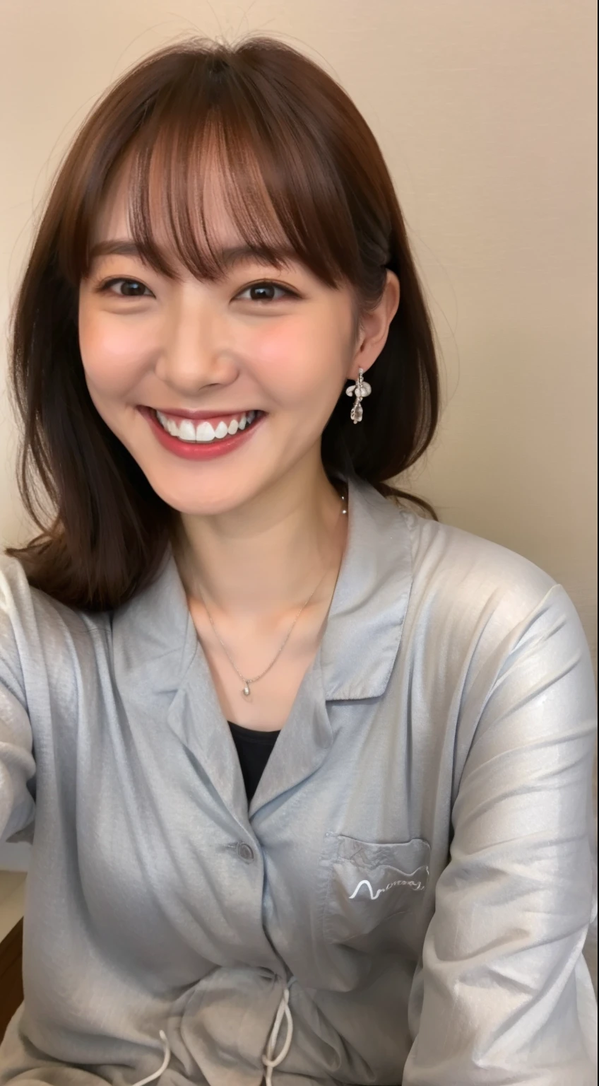 A Japanese woman wearing gray pajamas is sitting on the bed and smiling,ear piercing、smiling showing teeth、