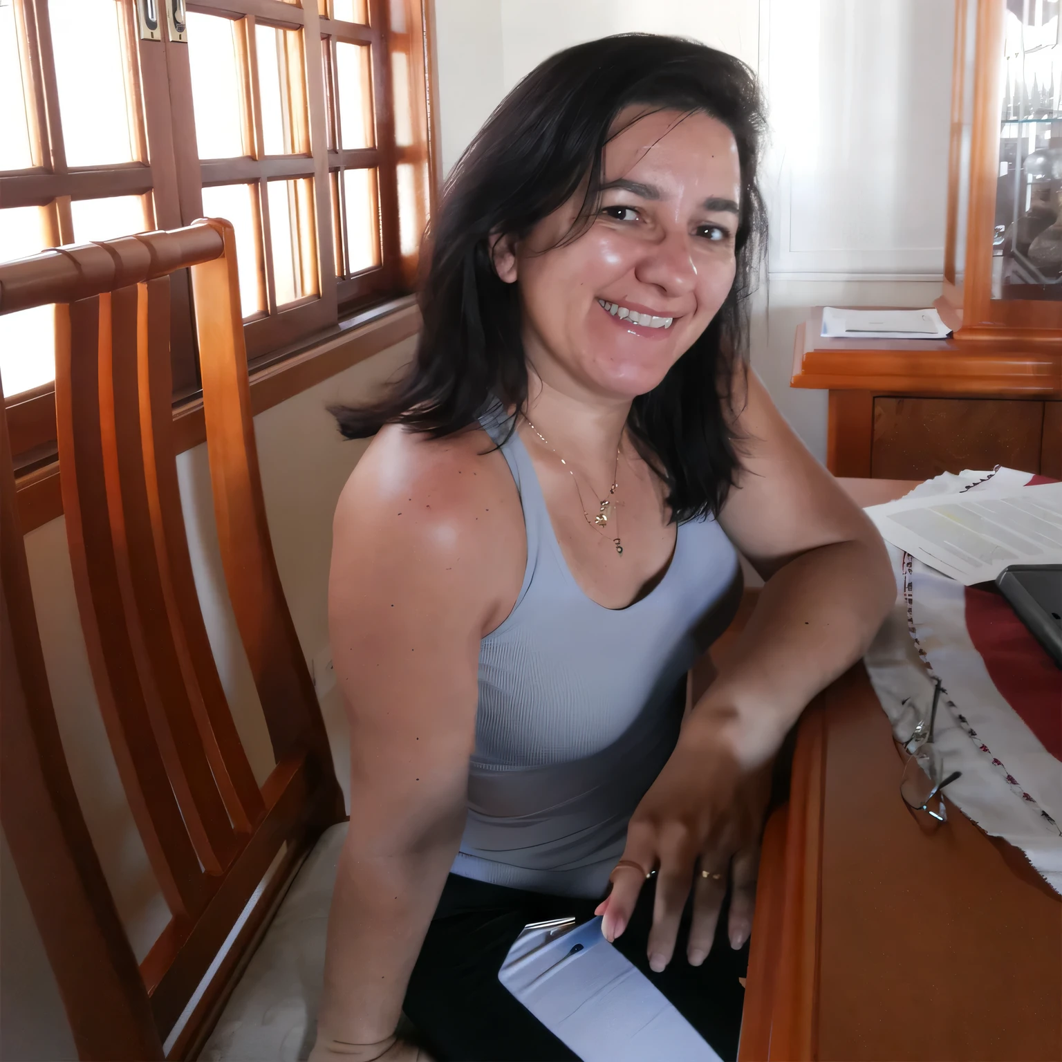 smiling woman sitting at the table with a laptop, 35 years old Brazilian. Woman in good physical shape. A woman with white skin and dark hair. She is about 35 years old. Her slightly plump red lips are like a delicate flower, her dark brown eyes seem to contain a world of wonders. Slim body. Thin waist. Her body exudes glamor and her face is the definition of beauty. Highly realistic, still, slightly full lips, pink lipstick, smile, feeling of lightness and joy, hyper-realism, very elaborate skin, look. Fitness woman. Sharp photo, high quality, high resolution, masterpiece, 8k.