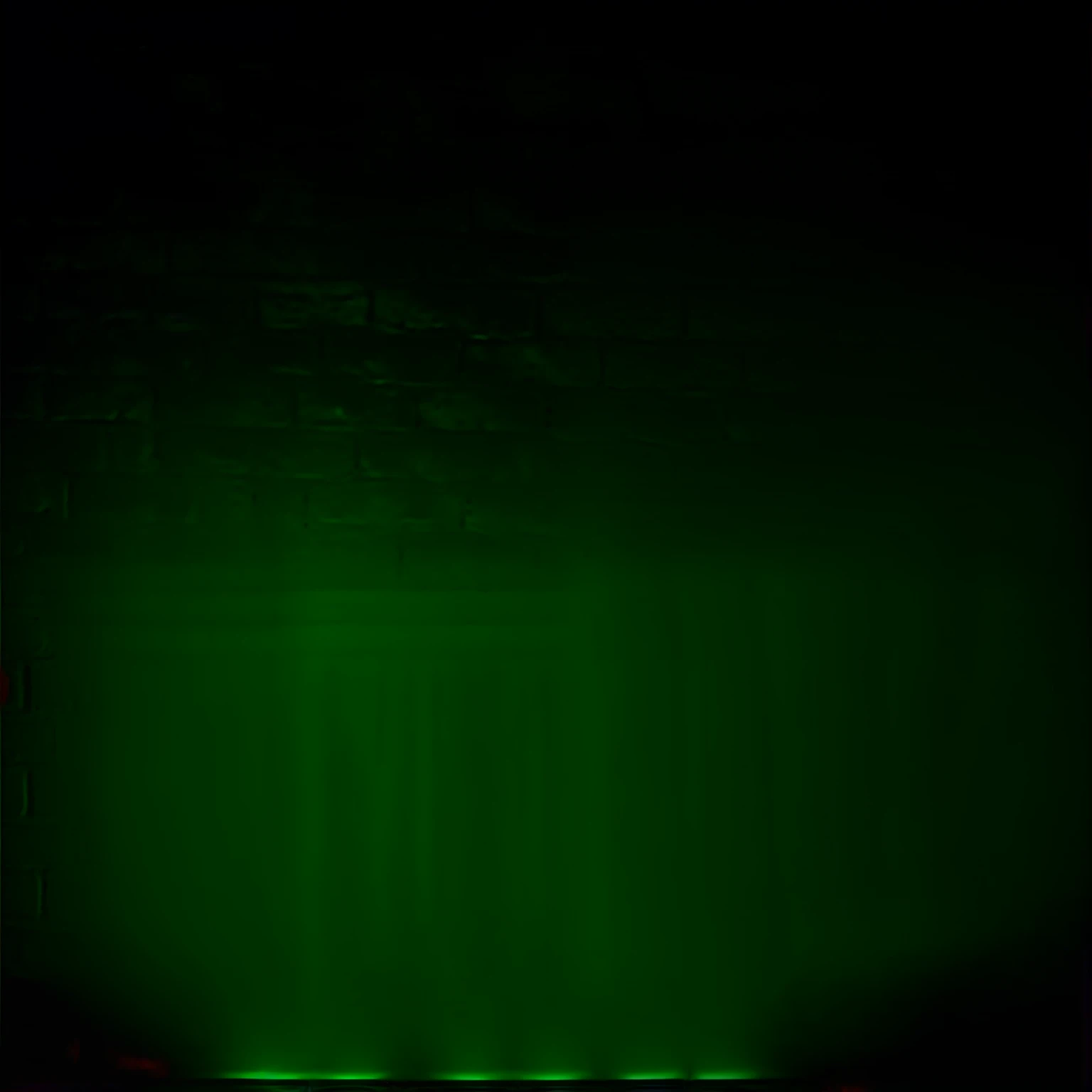 Inside of a dim lit bar with a large red neon sign the back wall that says “Don’t Do Drugs”, the wall is made of dark brick,