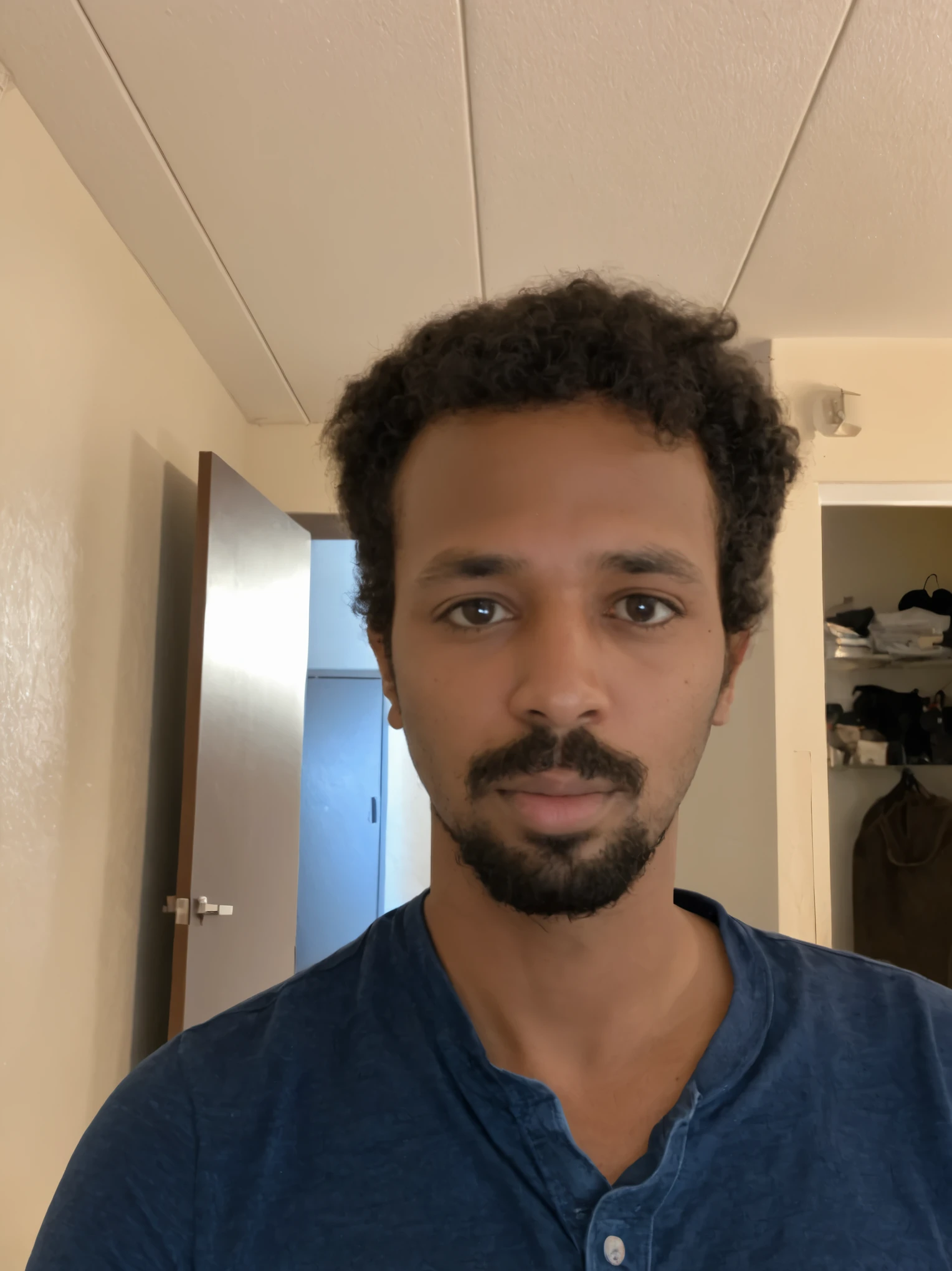 arafed man with a beard and a blue shirt sitting on a couch , east african man with curly hair, headshot profile picture, without beard, a black man with long curly hair, with a small beard, with no beard, without beard and mustache, taken in the early 2020s, 8k photograph, small beard, with trimmed mustache