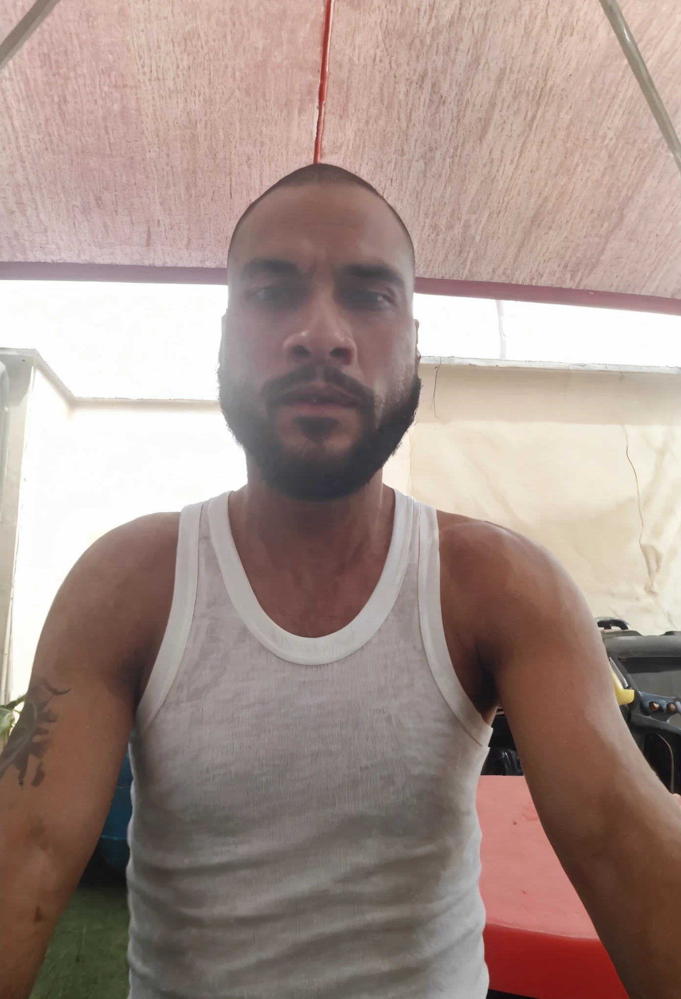 there is a man with muscular body a beard and a white tank top, very very low quality picture, about 3 5 years old, 2 9 years old, 2 7 years old, frontal picture, 3 2 years old, 4 0 years old man, 2 8 years old, 3 6 years old, around 1 9 years old, (38 years old)