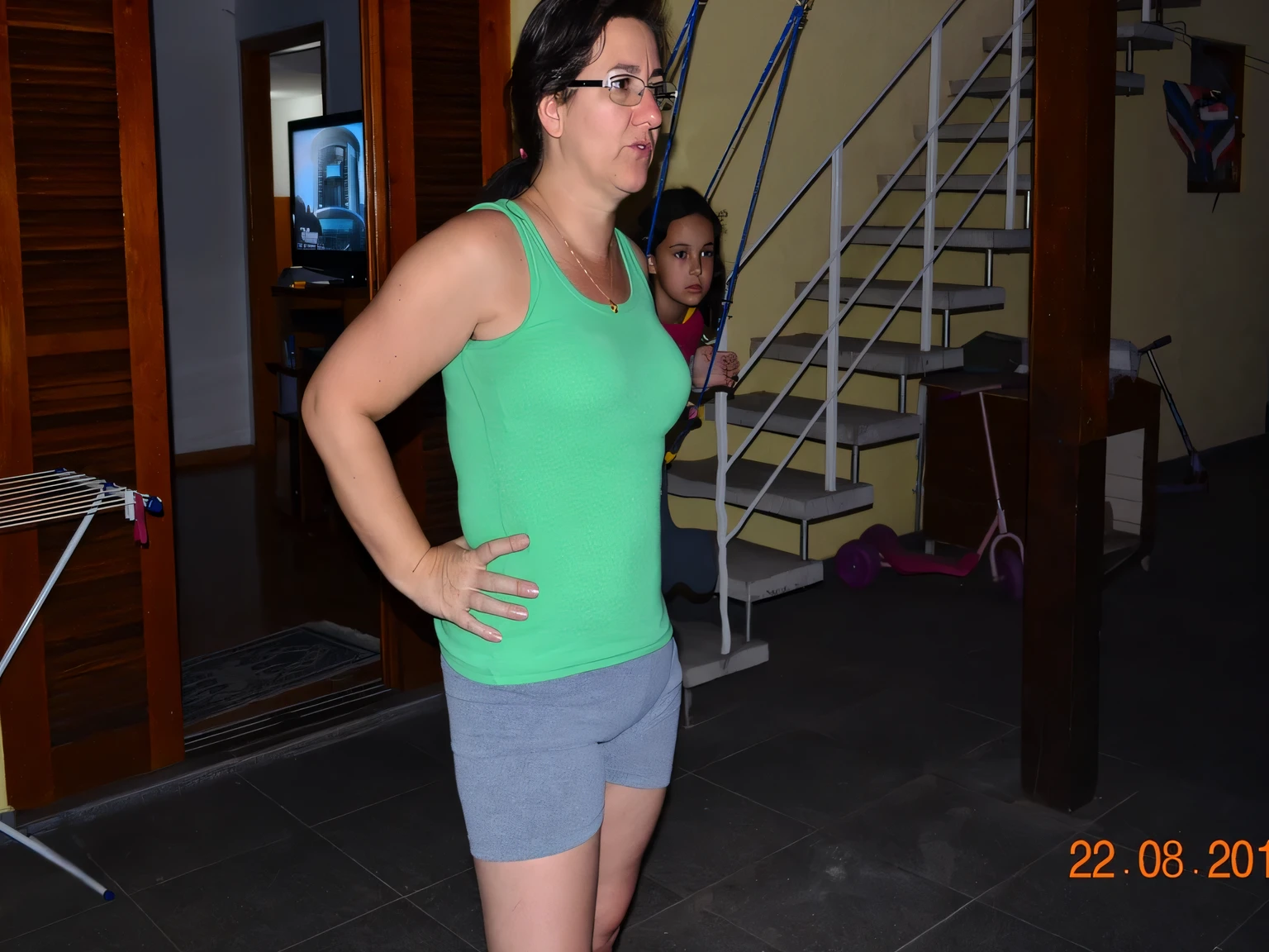there is a woman standing in a room with a wii remote, 3 5 year brazilian mother, side view of her taking steps, pilar, short robust woman, malika favre, 30-year-old woman from cuba, in good physical shape, fit, a broad shouldered, back and standing, fit pic, wearing a tank top and shorts