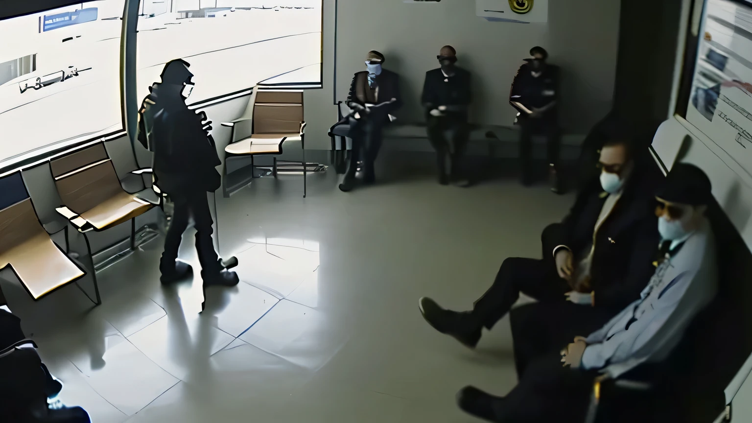 A man is walking with a shirt inside a black jacket and wearing sunglasses. He is not in the center. (Side view.) ((((Screenshot from a surveillance camera in an airport waiting room. People are sparse. Somewhat rough image quality but high quality. This was taken from diagonally above.)))