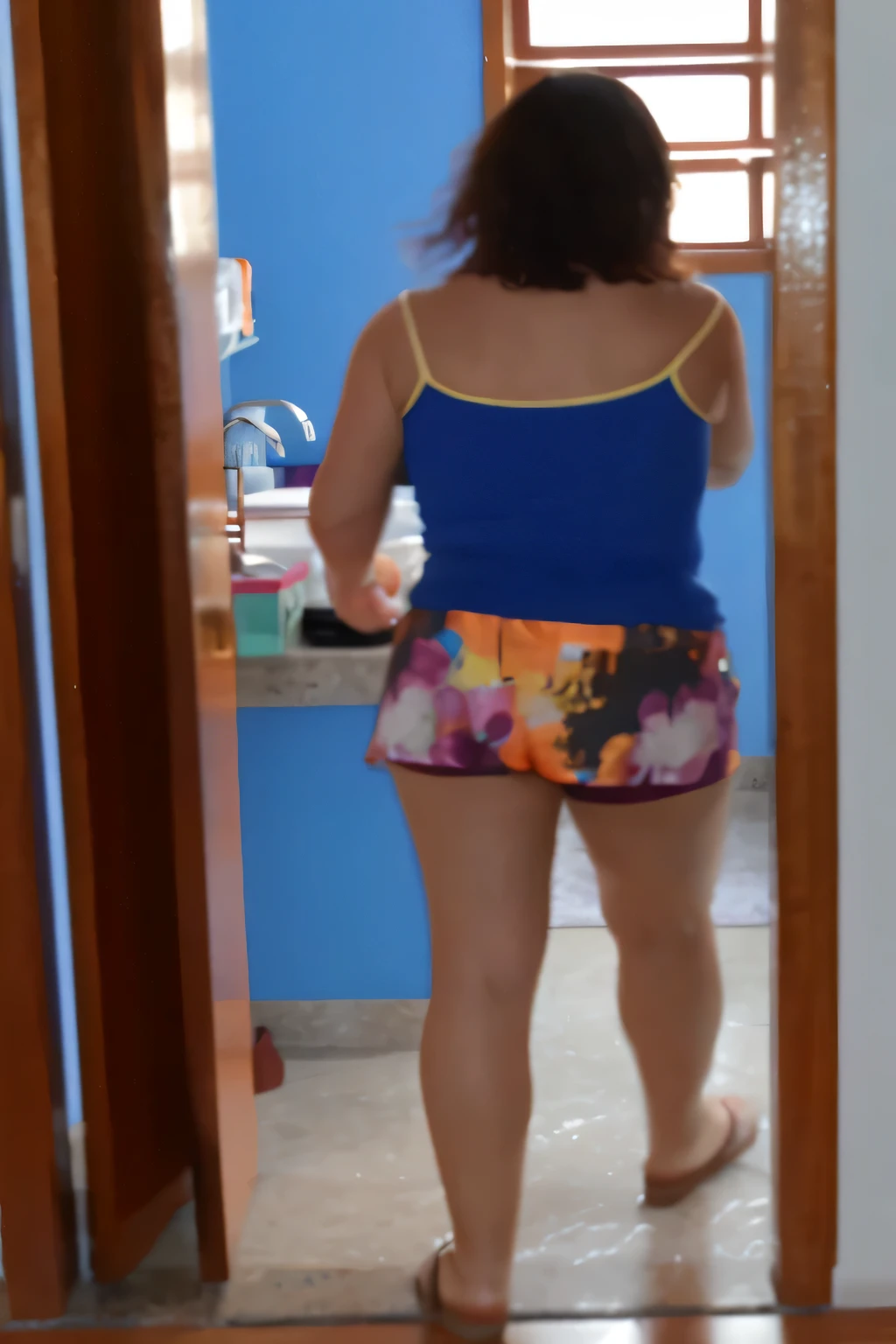 there is a woman standing in a doorway in a blue t-shirt, wearing a multicolored t-shirt and shorts, in shorts, wearing a tank top and shorts, dressed in a tank top and shorts, full body distant view, full body view, short shorts, photo side view, view behind the mirror, photo from the middle of the waist up, colorful clothing. A woman wearing a blue tank top and colorful shorts stands in the bathroom, looking at the counter. She appears to be focused on something or possibly taking a shower. The bathroom has a sink, table and miscellaneous items. Woman 1.65 m tall, weighing 54 kilos, in good physical condition, in good shape, wearing: tank top, high quality, high resolution, 8k.