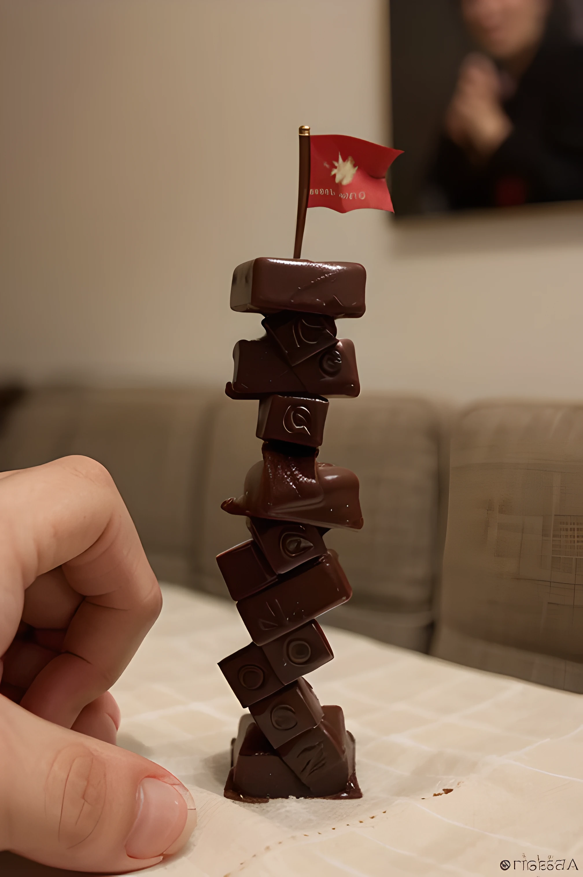 create a finished stack of chocolate chocolate cubes and a hand placing a small red flag on top of it, no estilo foto realista.