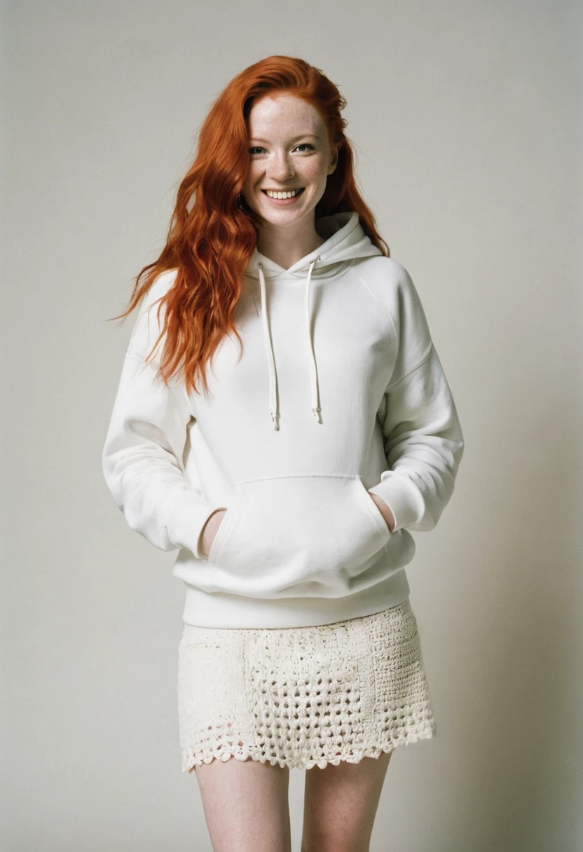 A full body front view red head woman swears an solid white ((off-hoodie)) sweatshirt with a front pocket. She also wears a crochet white skirt.The (((background is solid white)), smiling, cinematic, kodak portra 400.