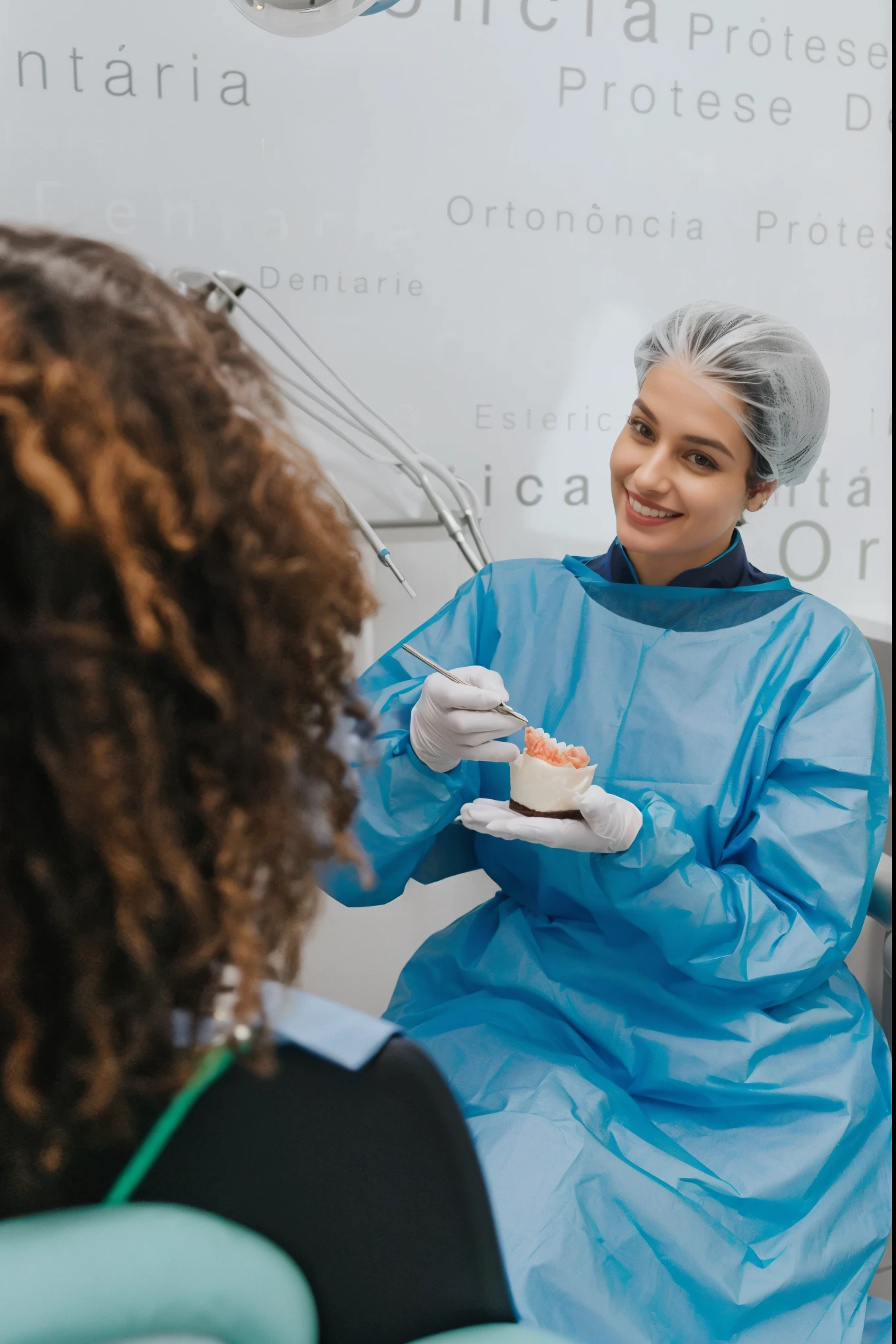 smiling mulher in blue gown sitting in chair with other mulher in chair, sorriso acolhedor, dentist, No fundo, by Amélia Peláez, healthcare professional, malika favre, surgical gown and lab coat, mulher, foto ainda, instagram post, medical photography, imagem completa, por Adam Marczyński, academia, por Matija Jama, surgeon