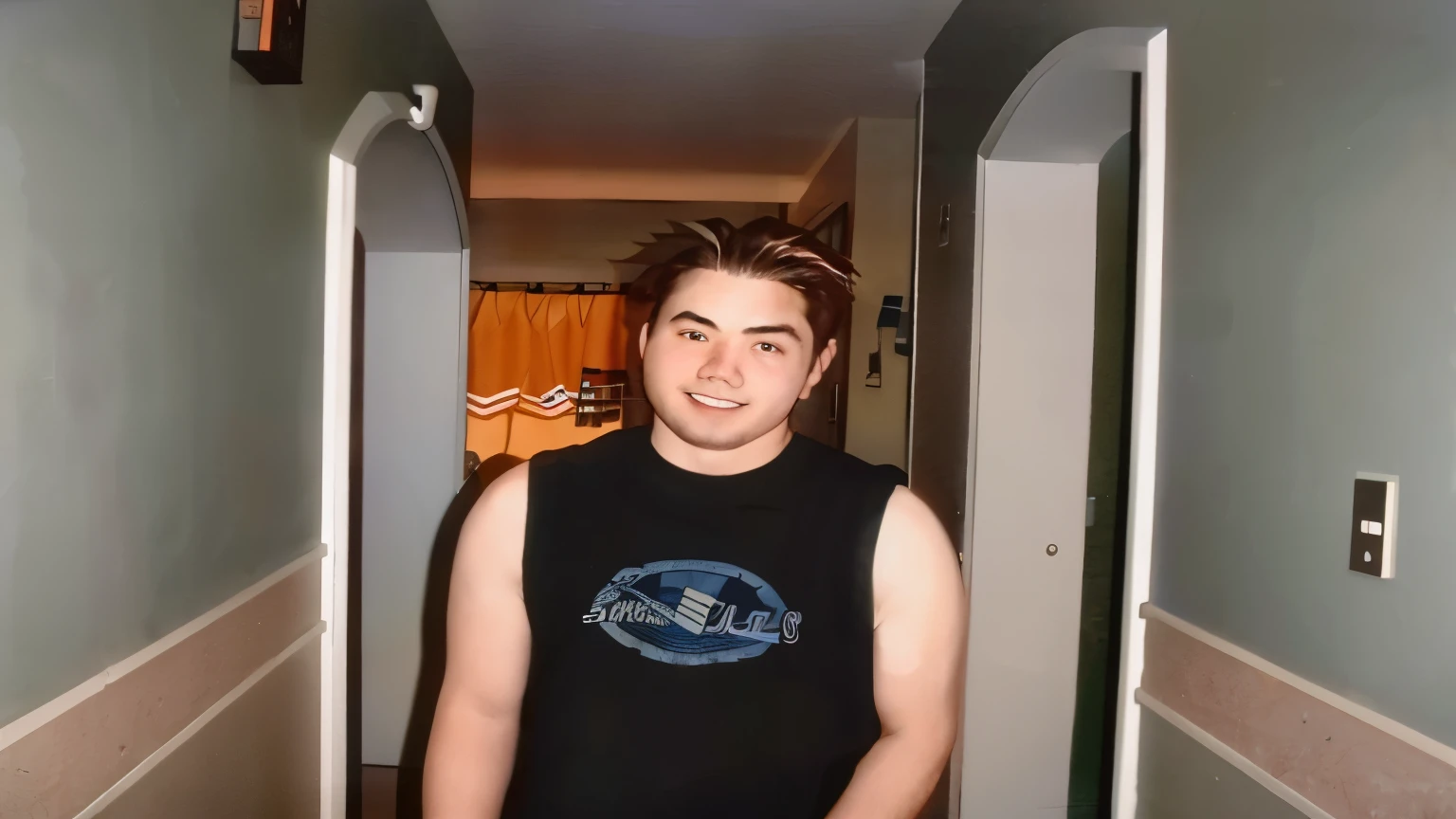 hay un hombre parado en un pasillo con una camisa negra, usando camiseta sin mangas, around 19 years, usando una camiseta sin mangas, he wears a black t-shirt, vistiendo una camiseta musculosa, taken in the mid 2000s, guapo chad chin, tommy 1 6 years, taken in the late 2000s, brandon