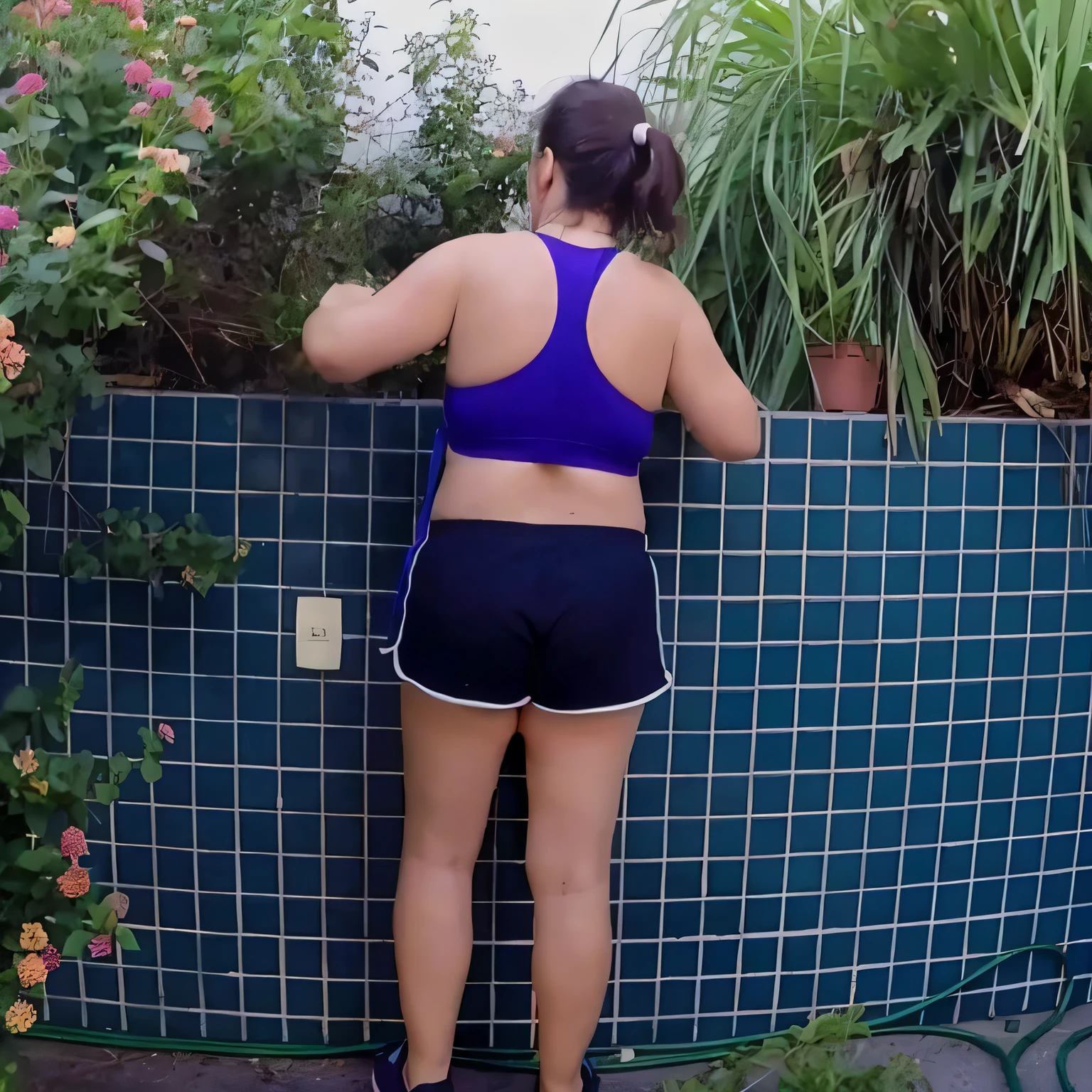 there is a woman standing next to a wall with flowers, back - shot, sport bra and dark blue shorts, squatting down next to a pool, fit pic, seen from the back, back pose, waist - shot, back shot, backview, shot from the back, sport bra and shorts, hunched shoulders, rear-shot, backshot. Best quality , high resolution, Masterpiece: 1.3, A high resolution, (photographically realistic), Beautiful girl, Sexy Pose, 8K, NFSW, fitness body, sports bra and dark blue shorts, toned legs. She is around 35 years old, a woman in good physical condition. Masterpiece, best quality, (best quality), realistic lighting, 8k.