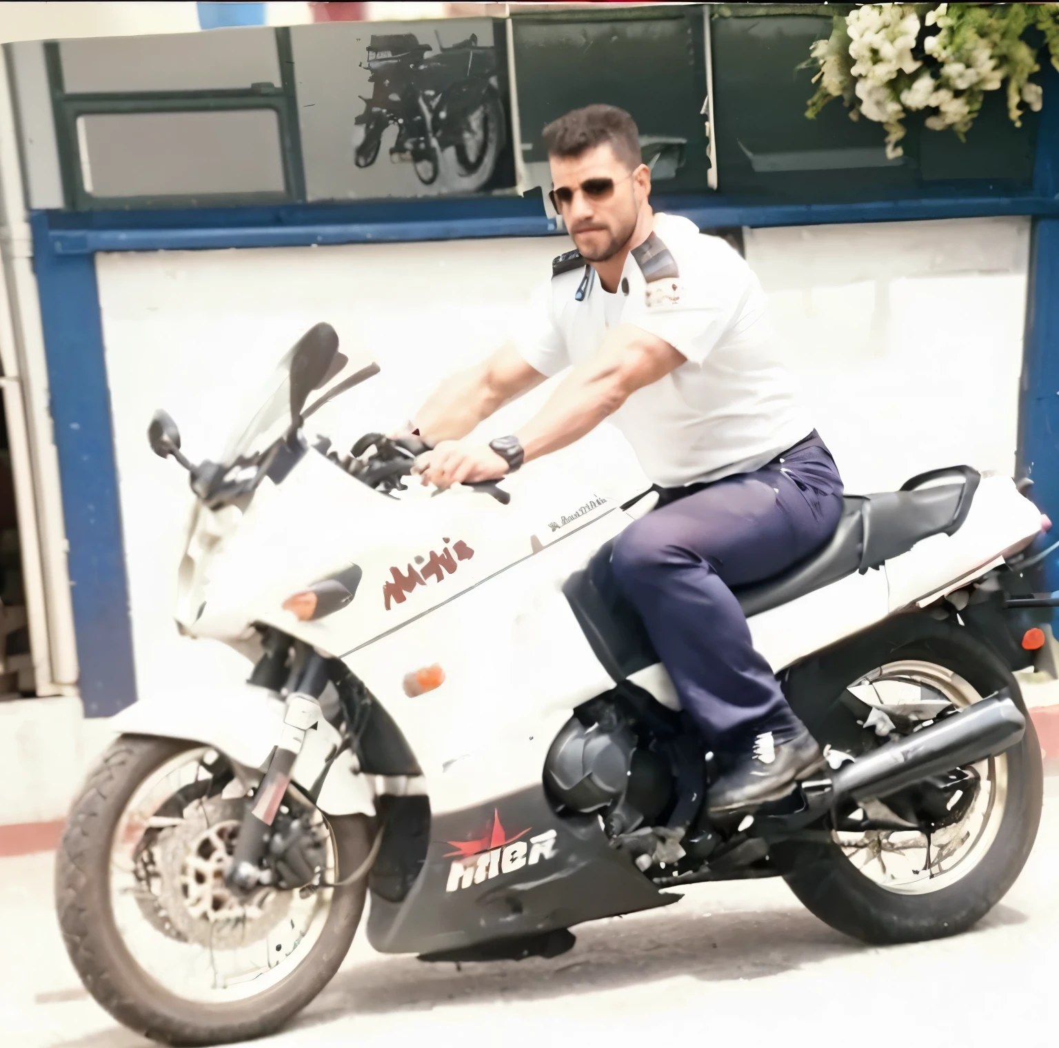 Hombre atractivo, en motocicleta, musculos marcados y uniforme militar., en camino con punto de fuga , y flores a lado del camino.