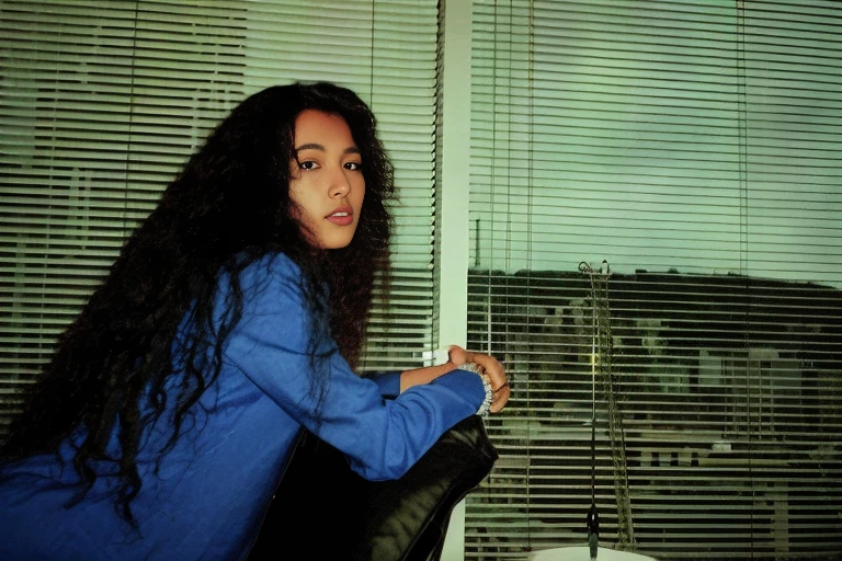 there is a woman sitting on a couch holding a remote, petra collins, in style of petra collins, basia tran, lofi portrait at a window, promo shot, sara ali, album art, petra collins and mc. escher, inspired by Nan Goldin, full colour, sza, photographic still, lisa, photo portrait, profile shot