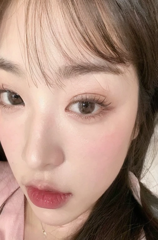 Un primer plano de una mujer con cabello largo y una camisa rosa, ulzzang, Jimin\his right eyelid is swollen, Hermoso rostro estetico, rasgos de la cara coreana, pale korean adorable face, maquillaje popular de corea del sur, joven y adorable rostro coreano, lindos ojos redondos e inclinados, ojos redondos y bien dibujados, ojos suaves y barbilla estrecha, maquillaje coreano popular