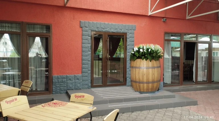 a large wooden barrel with pronounced staves, used as a flower garden, white flowers growing from the lid of the barrel,