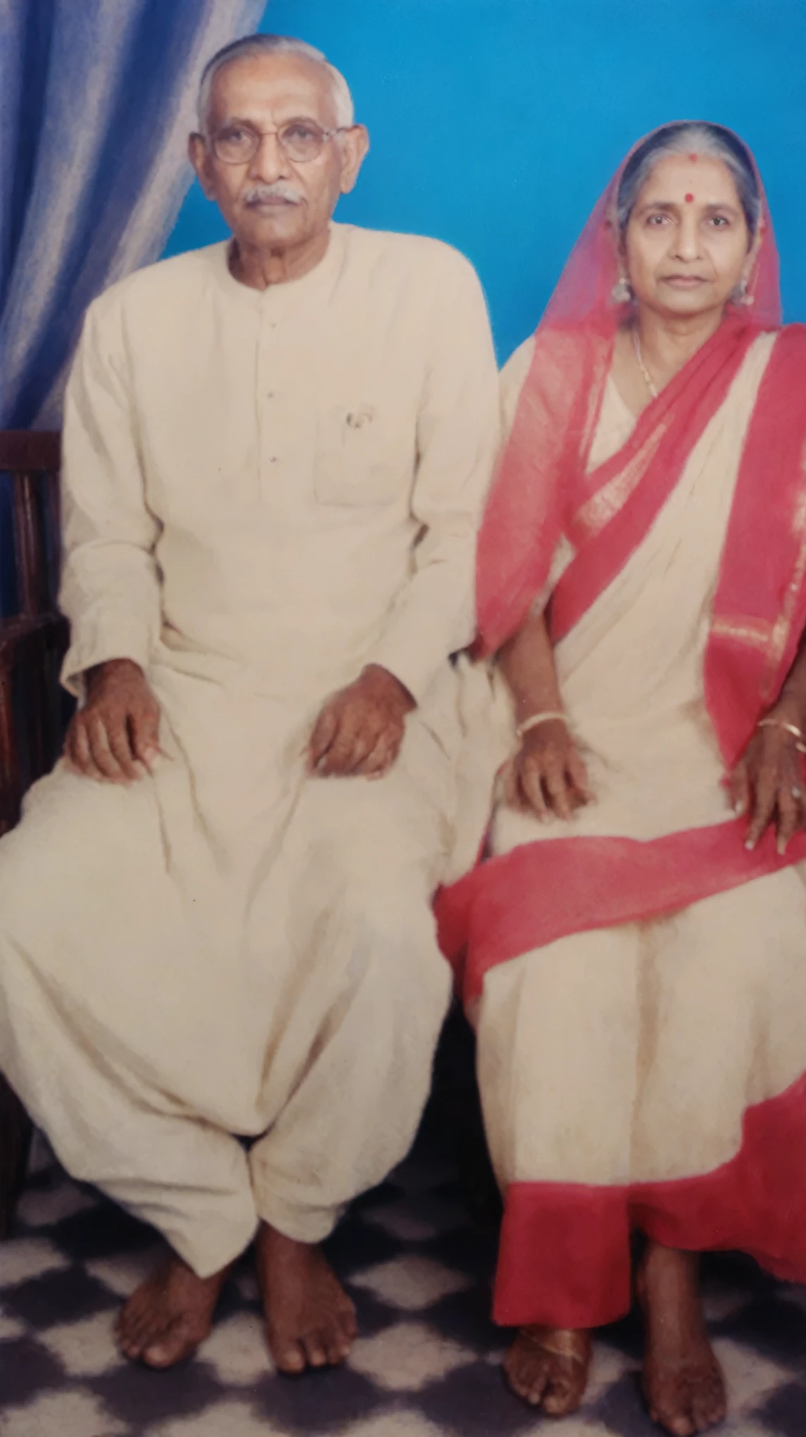 An old Indian couple, sitting on chairs, studio photo, capture timeless moment of the couple, the couple are mainly Bengali Hindu ethnicity, old timeless moments, restored old photo,