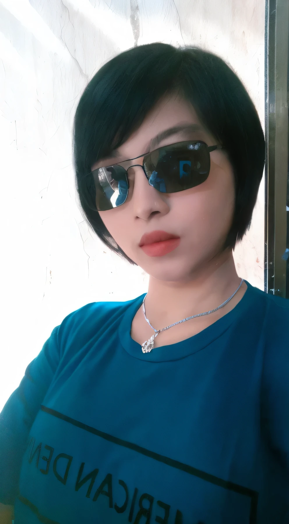 there is a woman wearing sunglasses and a blue shirt, with sunglass, with short hair, with sunglasses, selfie shot straight on angle, in sun glasses, 3 0 years old woman, 30 years old woman, potrait, wear ray - ban glass, photo on iphone, with accurate face, with very thin lips, cindy avelino, 2