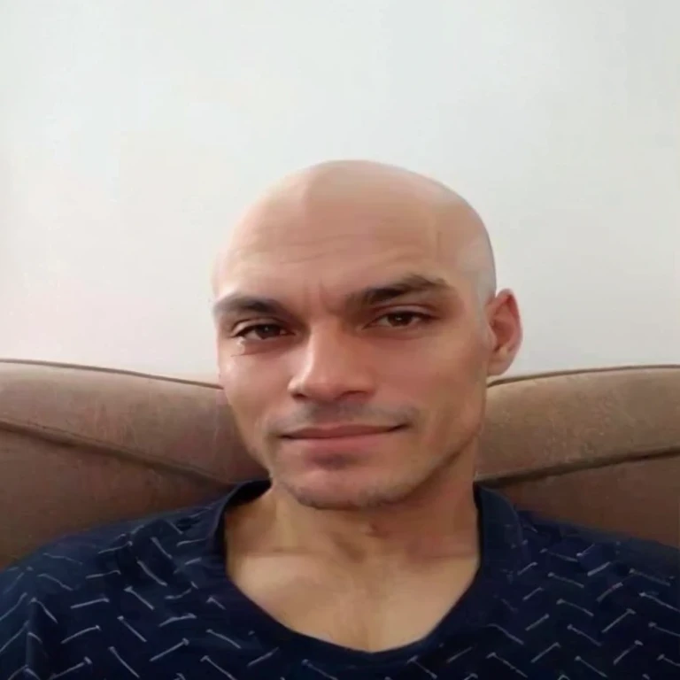 sharp man sitting on a sofa with a remote control in his hand, sem cabelo completely bald, barbeado face, shaved Careca, shaved head, careca com barba curta, rosto raspado, Careca, parcialmente careca, em breve um, muscle contraction coil / jogador ludwig, taken at the beginning of 2020, barbeado, sem cabelo, barbeado stubble