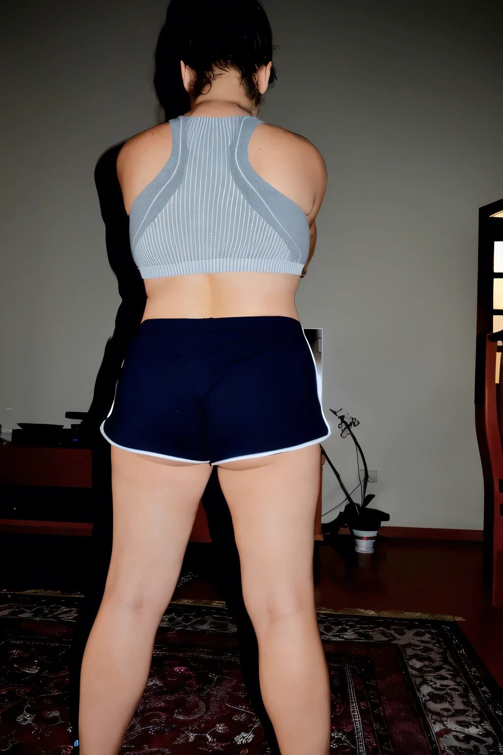 there is a woman in short dark blue shorts playing video games, sports bra and dark blue shorts, sports bra and shorts, back pose, back long shot, back view, arched back, back shot, back long shot, rear view , back photo, back photo, back view, back view, back photo, photo taken from the back, toned back, working out, back pose, action pose, toned back, making a cheeky pose, extremely hot and sexy. back photo, toned back, back photo, from behind. Beautiful woman, perfect body, 38 years old, beautiful woman, dark brown eyes, ((beautiful slim woman, 38 years old, hair color [black hair], slim waist, charming, fair skin, (sexy), (detailed face) , detailed eyes, (hot), beautiful body and soft, voluptuous woman, crop top, thong, shorts, ((full body))