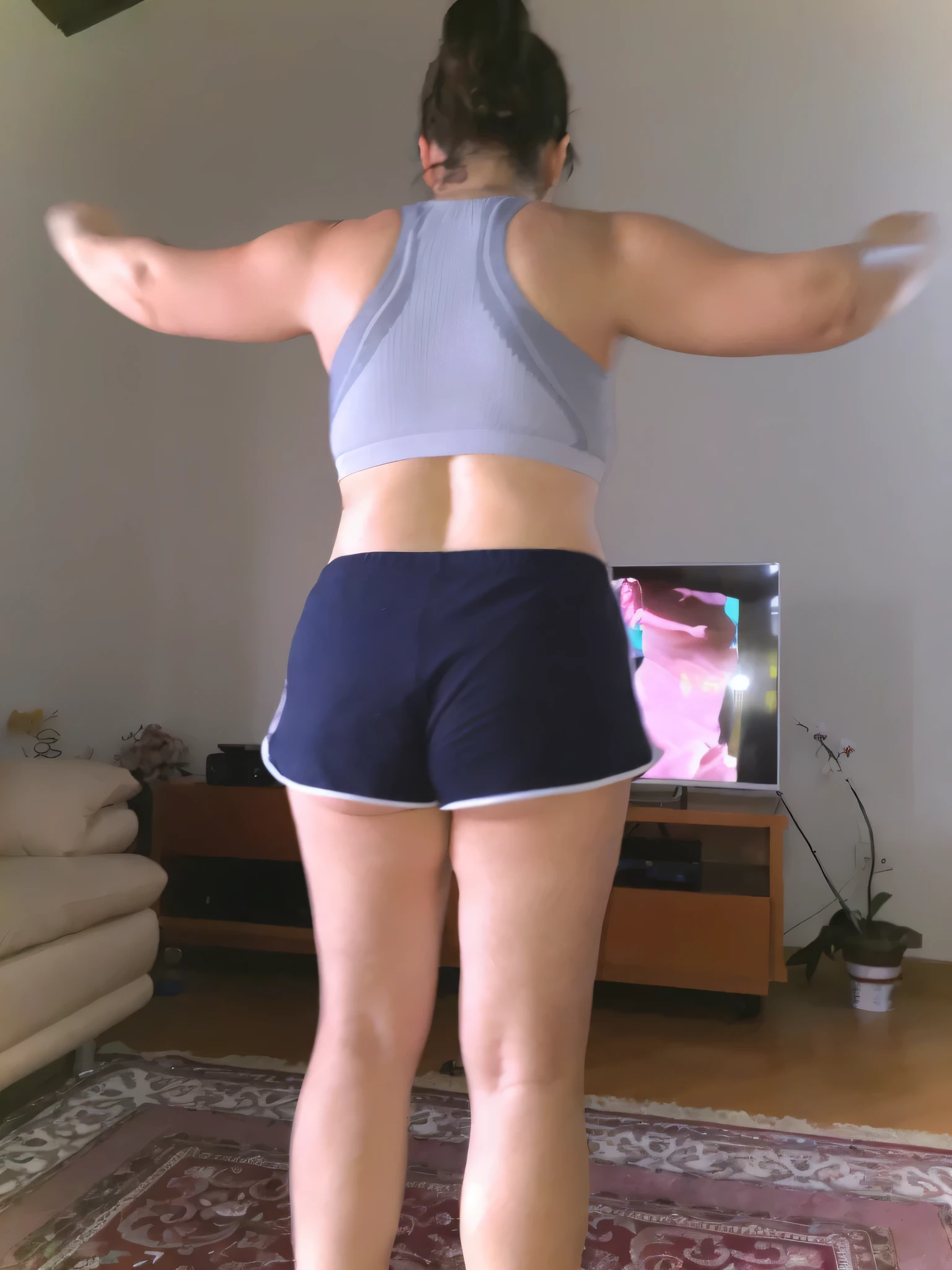 A beautiful light brunette woman, raising her hands, in a gray top and very short dark blue sports shorts, standing in a living room, in shorts, general shot of the back, seen from the back, view from the back, grayish sports bra and blue shorts dark, back view, long shot of back, very short pants, back views, back photo, back views, back, rear view, photo taken from the back, with tanned body, toned body, athletic body, (( ((legs)))); sexy pose, extremely sexy, very sensual, shapely legs. She is about 36 years old, 1.62 tall, 60 kg, best quality, perfect face, perfect mouth, perfect hands, is standing, (full body) wearing a tank top (((grayish top))), blue shorts tight dark blue shorts (((dark blue shorts))), short blue shorts for gym training, well defined, her slightly plump and red lips look like a delicate flower. Slim body, slim waist. Her body exudes glamor and her face is the definition of beauty. Highly realistic, reddish skin, feeling of lightness and joy, hyper-realism, very elaborate skin. Sharp photo, high quality, high resolution (ultra quality masterpiece), Ultra HD, high contrast, 16K. Masterpiece: 1.3, high resolution, (photographically realistic), 8k, NUDE, NUDITY, NFSW.