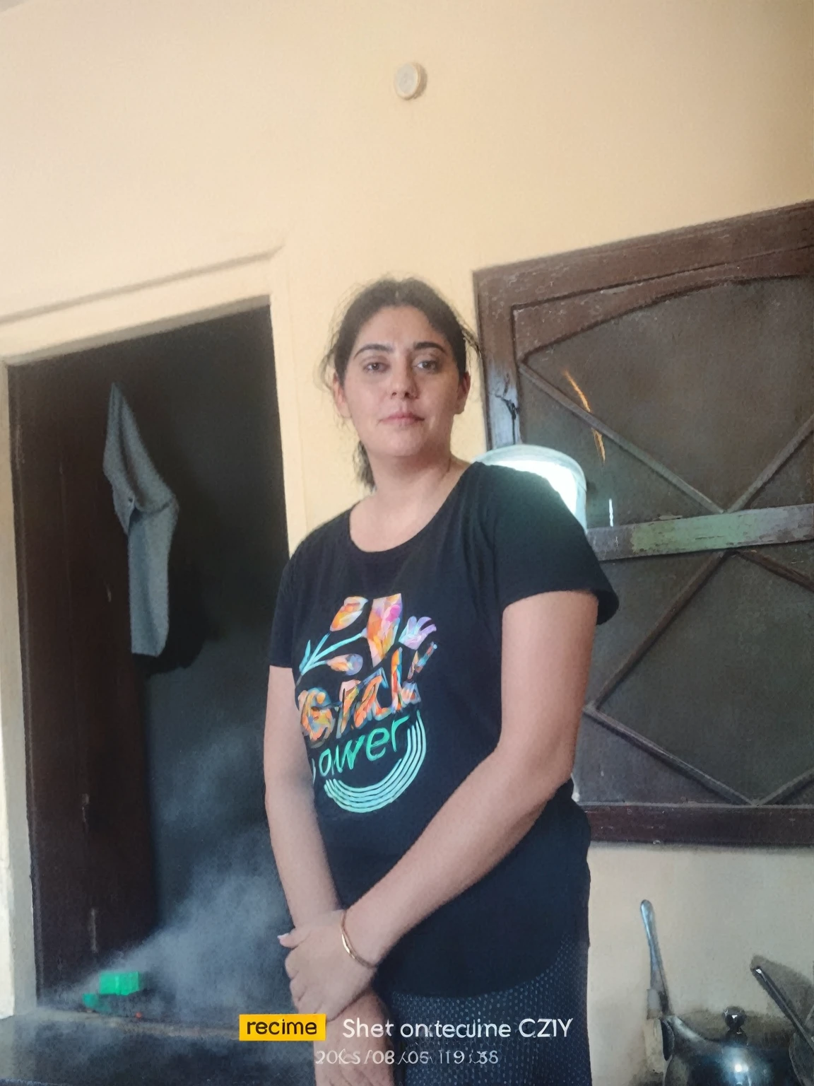 there is a woman standing in a kitchen with a black shirt, 30 years old woman, 3 0 years old woman, very very low quality picture, photo taken in 2 0 2 0, 3 0 years woman, she is about 2 5 years old, portait image, around 1 9 years old, she is about 30 years old