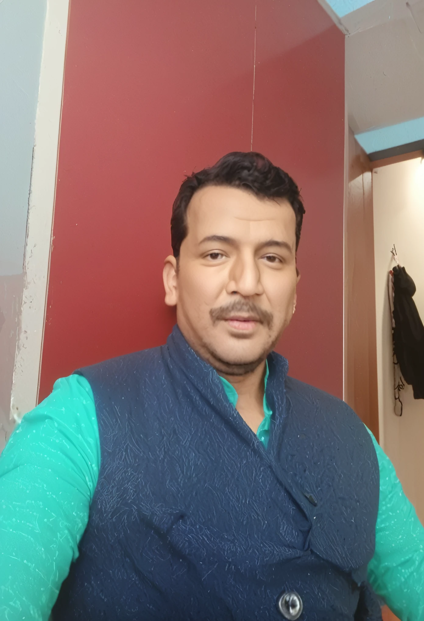 there is a man standing in a room with a red wall, 4 0 years old man, ranjit ghosh, without helmet, with accurate face, vastayan, a photo of a man, inspired by Kailash Chandra Meher, very very low quality picture, assamese, vinayak, without beard, by Rajesh Soni, about 3 5 years old