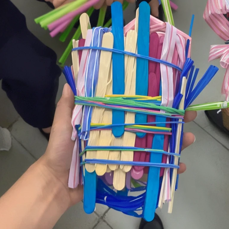 there is a person holding a basket of pops sticks and flowers, straw, unknown artist, with a straw, artist unknown, art project, giant claws loom, colored, fully colored, made of lollypops, by Amelia Peláez, by Kanbun Master, highly creative, made of candy and lollypops, tiny sticks, paper quilling, description