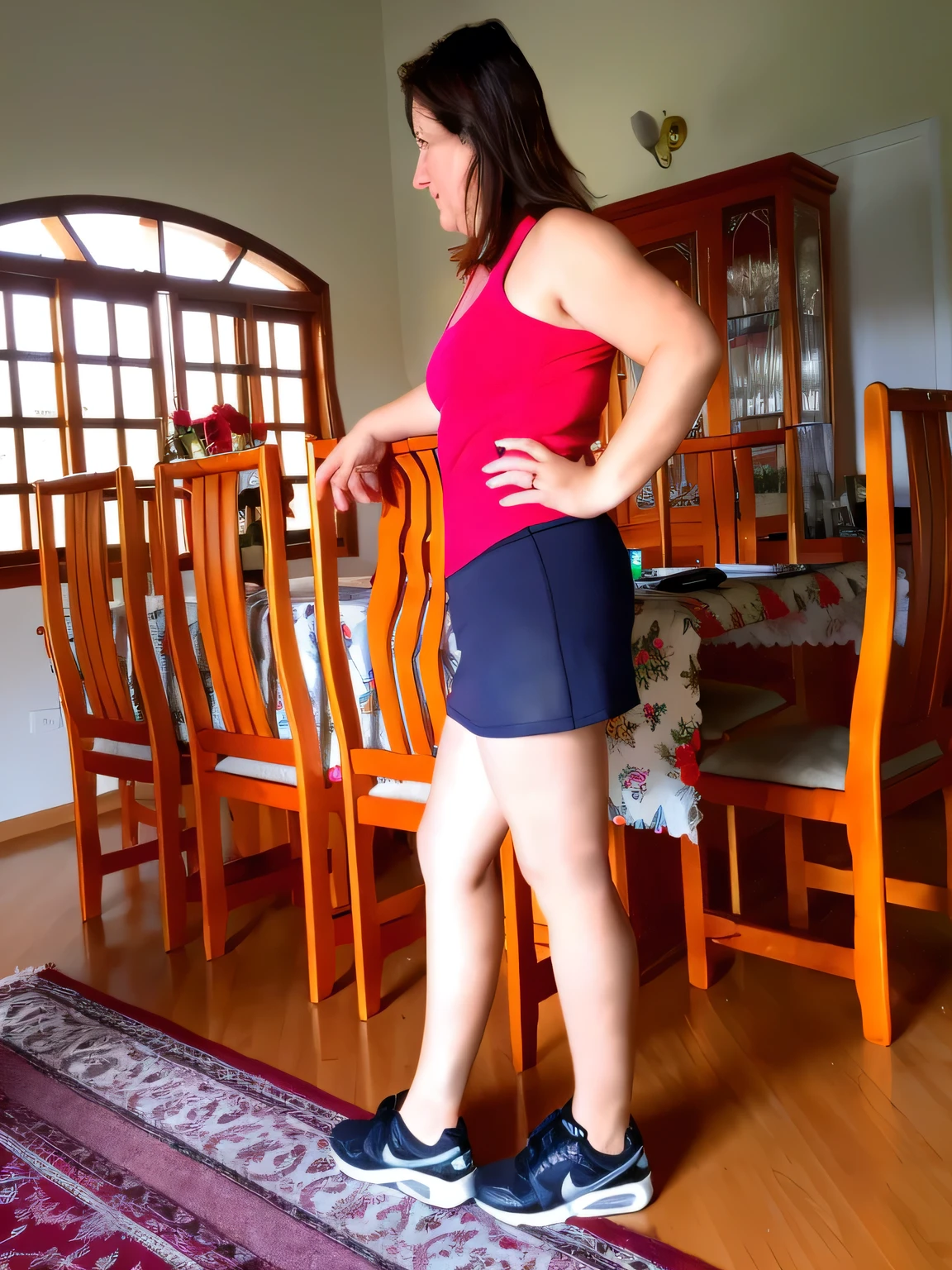 there is a woman standing on a rug in a room, side shot, side pose, side portrait, wearing red shorts, in shorts, side view of her taking steps, sport bra and dark blue shorts, short robust woman, full length view, side profile shot, lunging at camera :4, posed in profile, from side, middle shot waist up