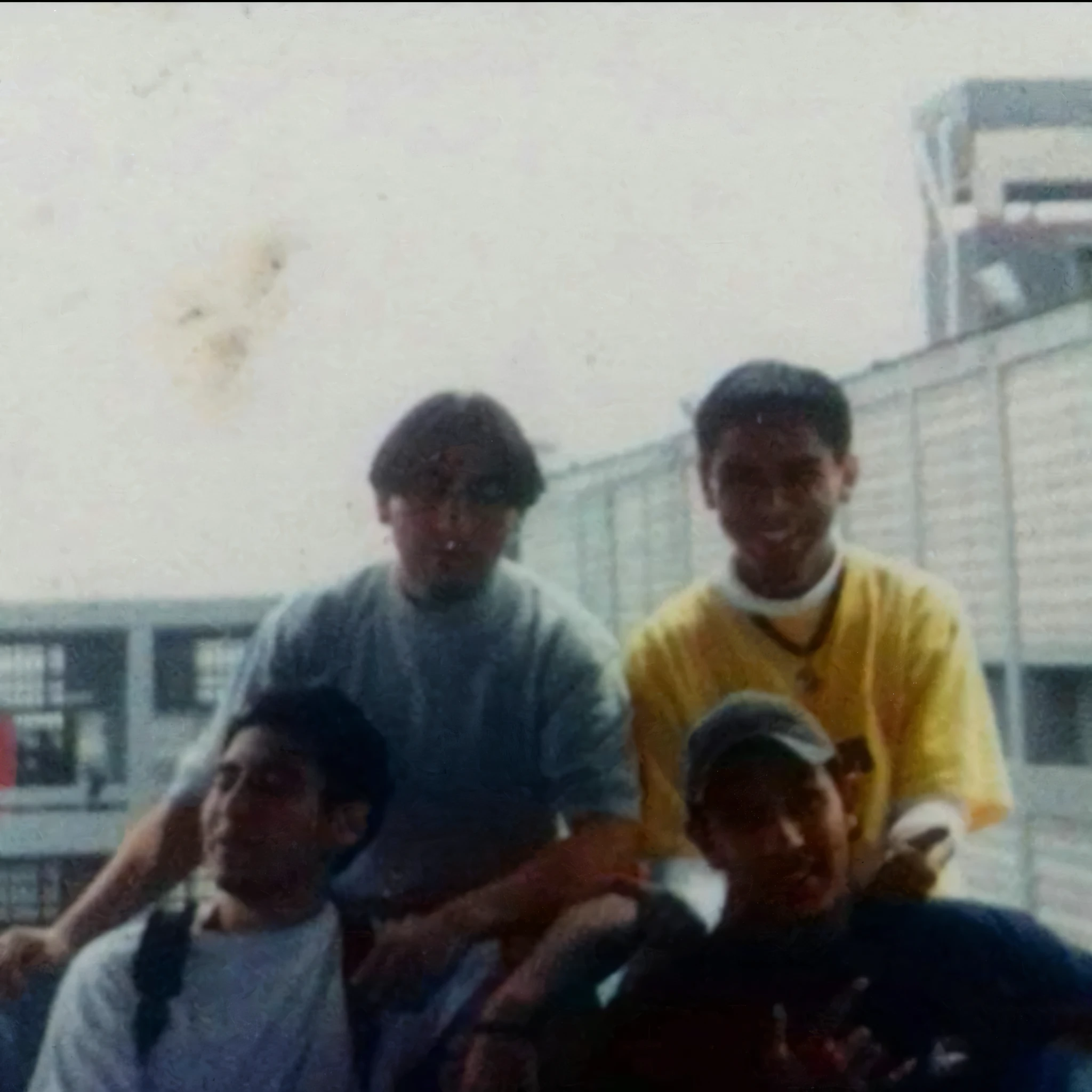 Hay cuatro hombres sentados juntos en un banco en la ciudad., foto en color de los 90, taken in the early 1990s, foto de los 90, foto de los 90, 19foto de los 90, viejo cuadro, tomado en 1 9 9 7, granoso photo, foto 1 9 9 0 s, granoso, amigo de la infancia  