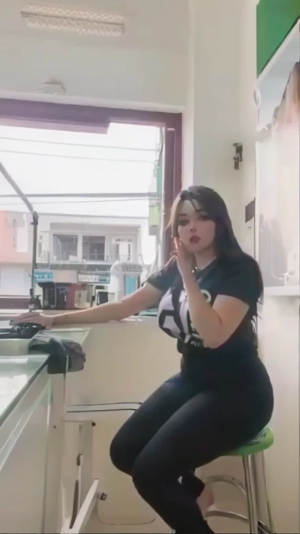 there is a woman sitting on a stool in a room, low quality video, tiktok video, sexy girl, at the counter, sie boob, low quality footage, she is facing the camera, she is posing, sexy pose, behind her is a scary atmosphere, in the style of sifu 🔥 😎 🕹️ 👀 :2, gif, thicc.high resolusi.ultra HD