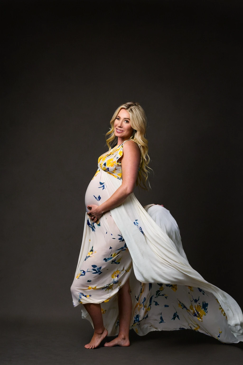 pregnant woman in yellow floral  dress posing for a studio photo, blond hair , backdrop with blue  marble paper Persian calligraphy , full length view, wearing a yellow flowing dress, full body wide shot, full length shot, full body photoshoot, pregnant belly, long flowing yellow robe, draped in flowing fabric, posed, studio portrait photography, flowing white robes, full length photo, full - length photo, studio photography portrait