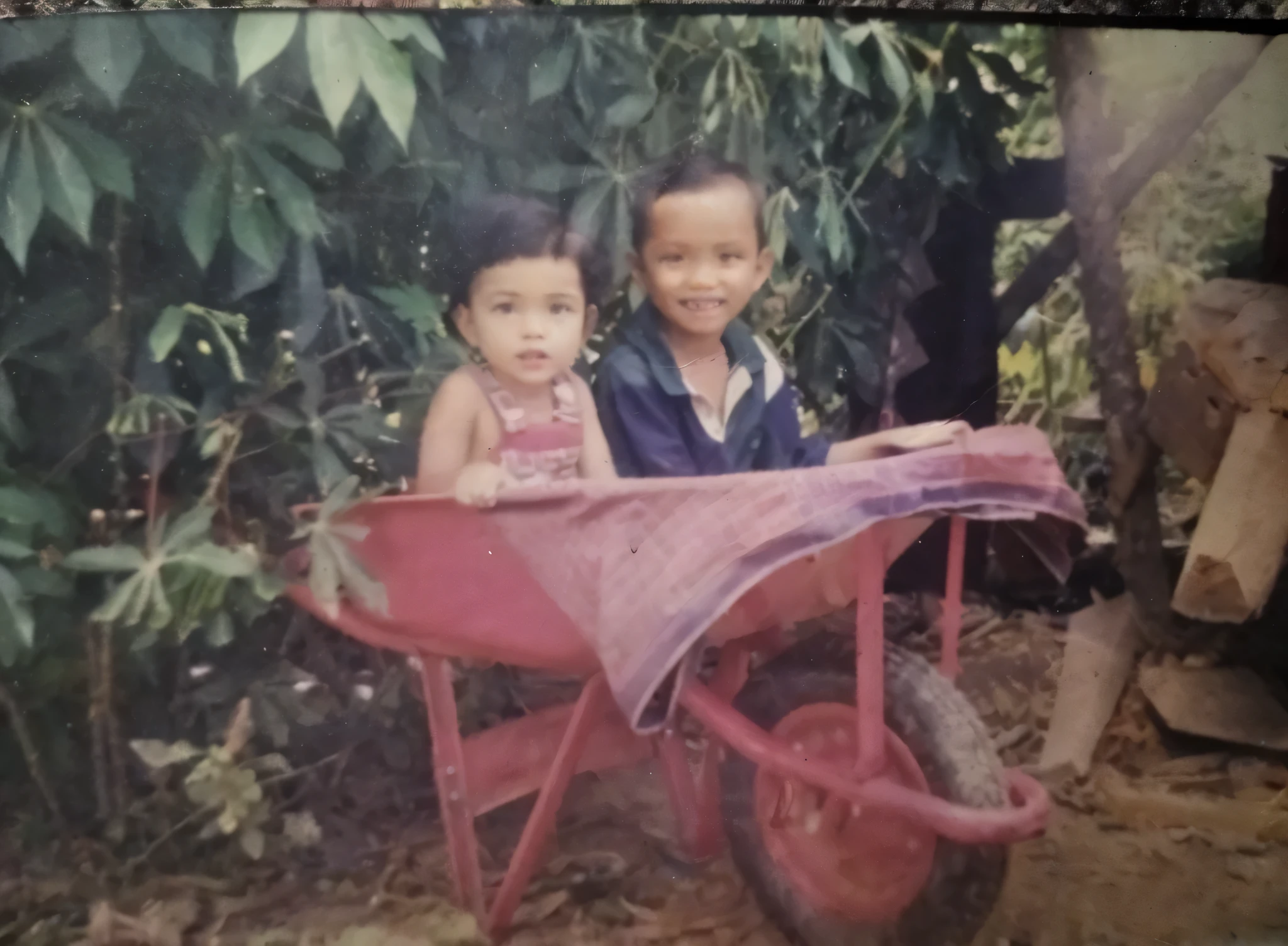 there are two children sitting in a red wheelbarrow, old picture, childhood friend, old photo, childhood memory, analog photo, very old photo, with a kid, old style photo, cute photo, photo on iphone, foto, very very low quality picture, help me, album photo, potrait, 1 9 8 0 s photo, 1980s photo