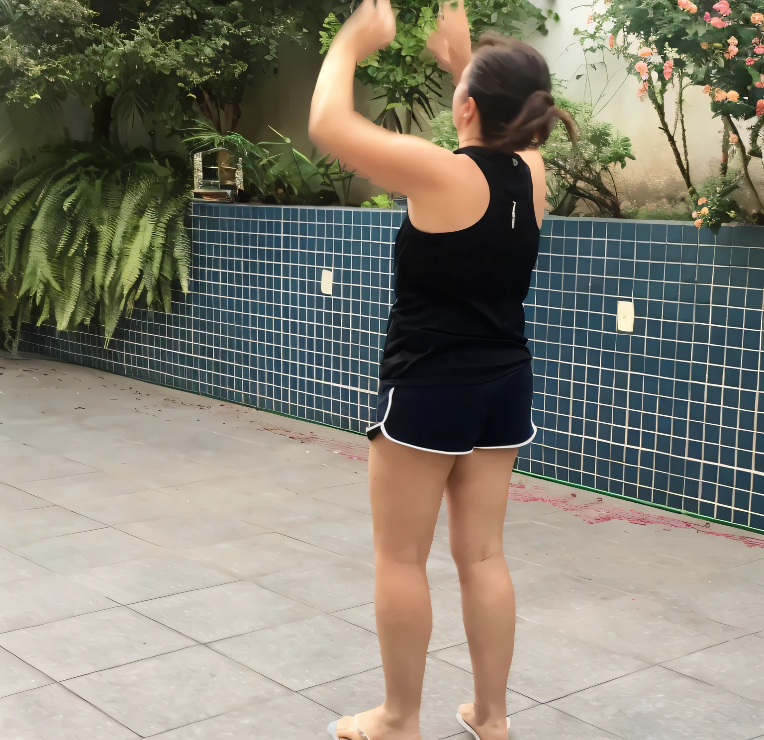 woman in black shirt and shorts playing with a frisbee on a tiled patio, squatting down next to a pool, side view of her taking steps, back - shot, back and standing, backshot, back pose, in full growth from the back, outside, long shot from back, twirling, back - view, full growth from the back, back shot