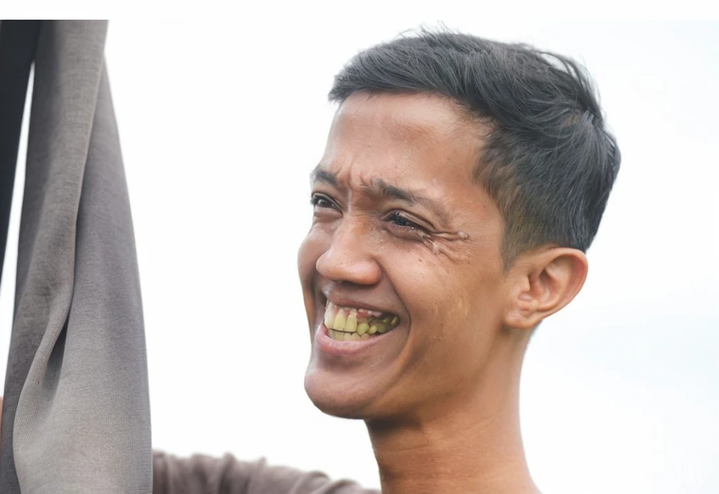 there is a man smiling and holding a cell phone in his hand, smiling man, candid portrait, smiling warmly, with a beautifull smile, insane smile, smiling male, brown skin man with a giant grin, very very happy, joyful look, very big smile, mutahar laughing, earing a shirt laughing, right - half a cheerful face, friendly smile