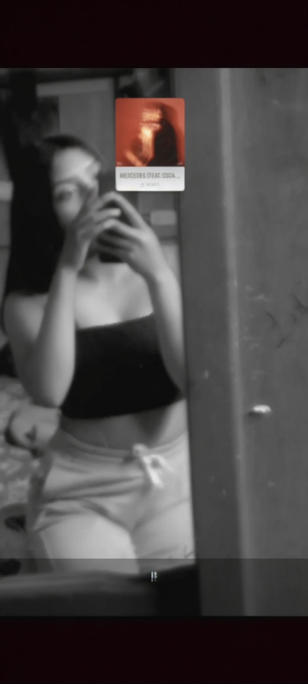 brunette girl photographing herself in front of the mirror. You can only see half his body and his face covered by the cell phone.. Black and White Photography.