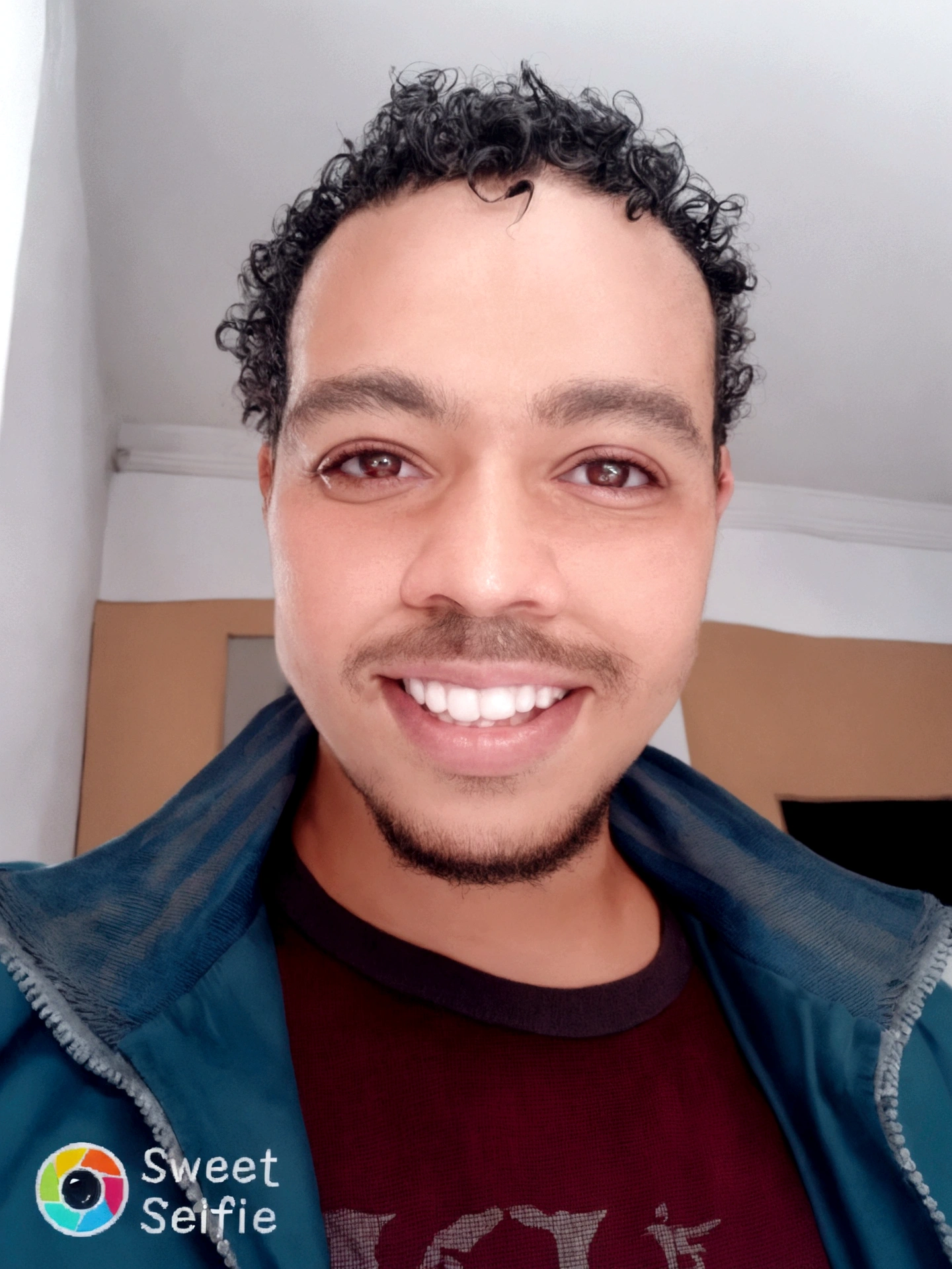homem sorridente com cabelos cacheados e uma jaqueta, Mohammed Chahin, caio santos, icaro carvalho, atef., david rios ferreira, Riyad Cassiem, Mohamed Reda, East African man with curly hair, edu souza, ismail, sorrindo e olhando diretamente, Saâdane afif, outras shulzes, carmelo blandino, sem barba