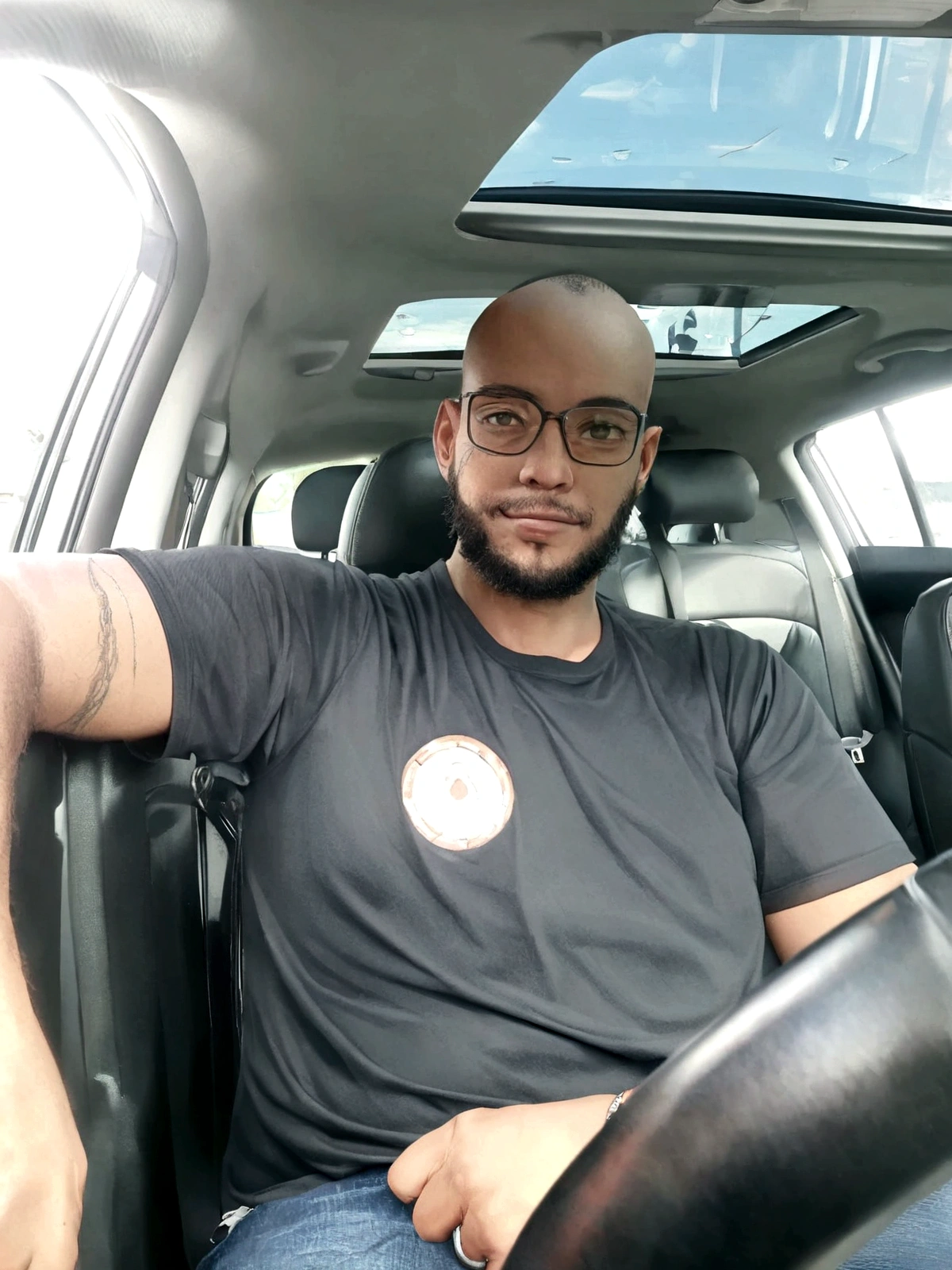 bald, with beard, smiling, black shirt and wears glasses