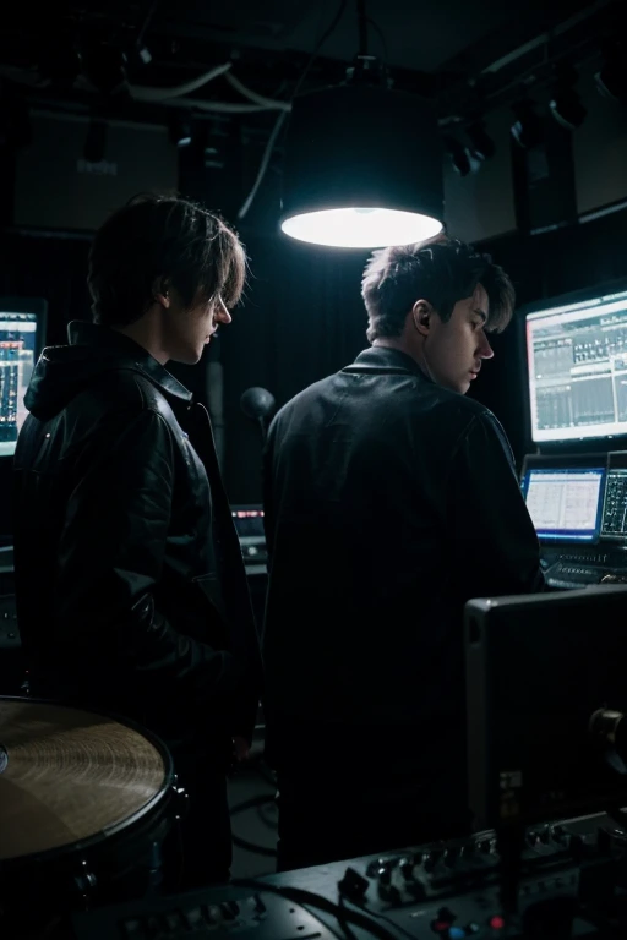 2 male music artists making and recording music in studio at nights don't show their faces either blur them with dark lighting in the studio