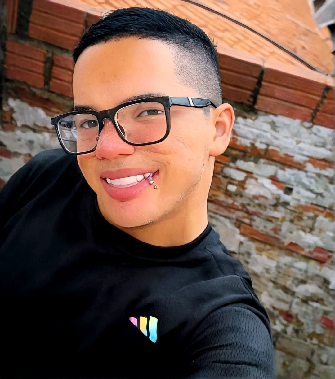 
create a smiling man with glasses, wearing a black shirt, with a wall in the background as if he were a Disney and Pixar character