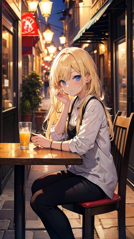 Blonde girl sitting in a street cafe in the evening