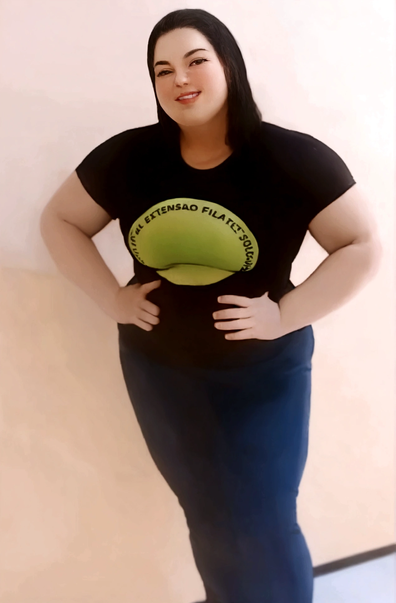 Caucasian woman, black hair, a little fat, standing, wearing a black blouse and pants, with her hand on her waist and smiling