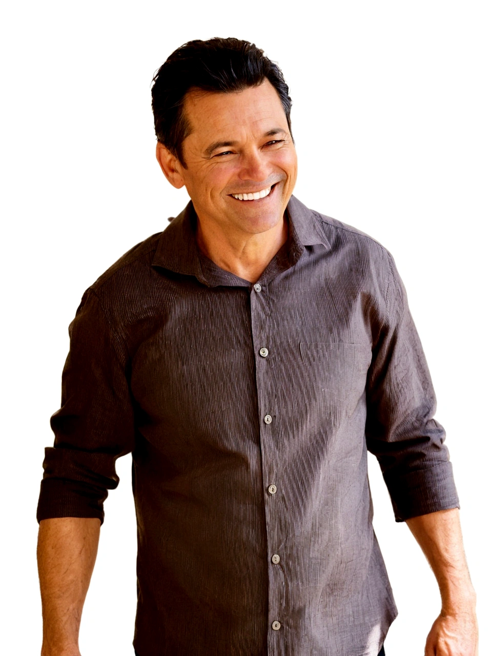 smiling 45-year-old man, brown button-down shirt, black hair, he is standing against a white wall