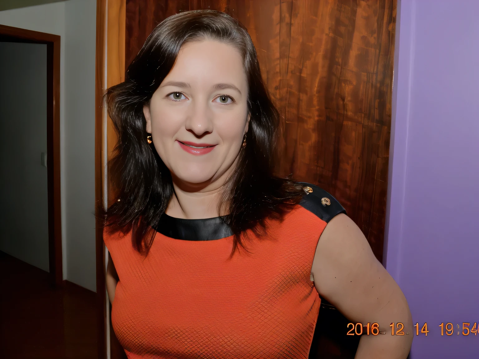 smiling woman in orange dress standing in front of a door