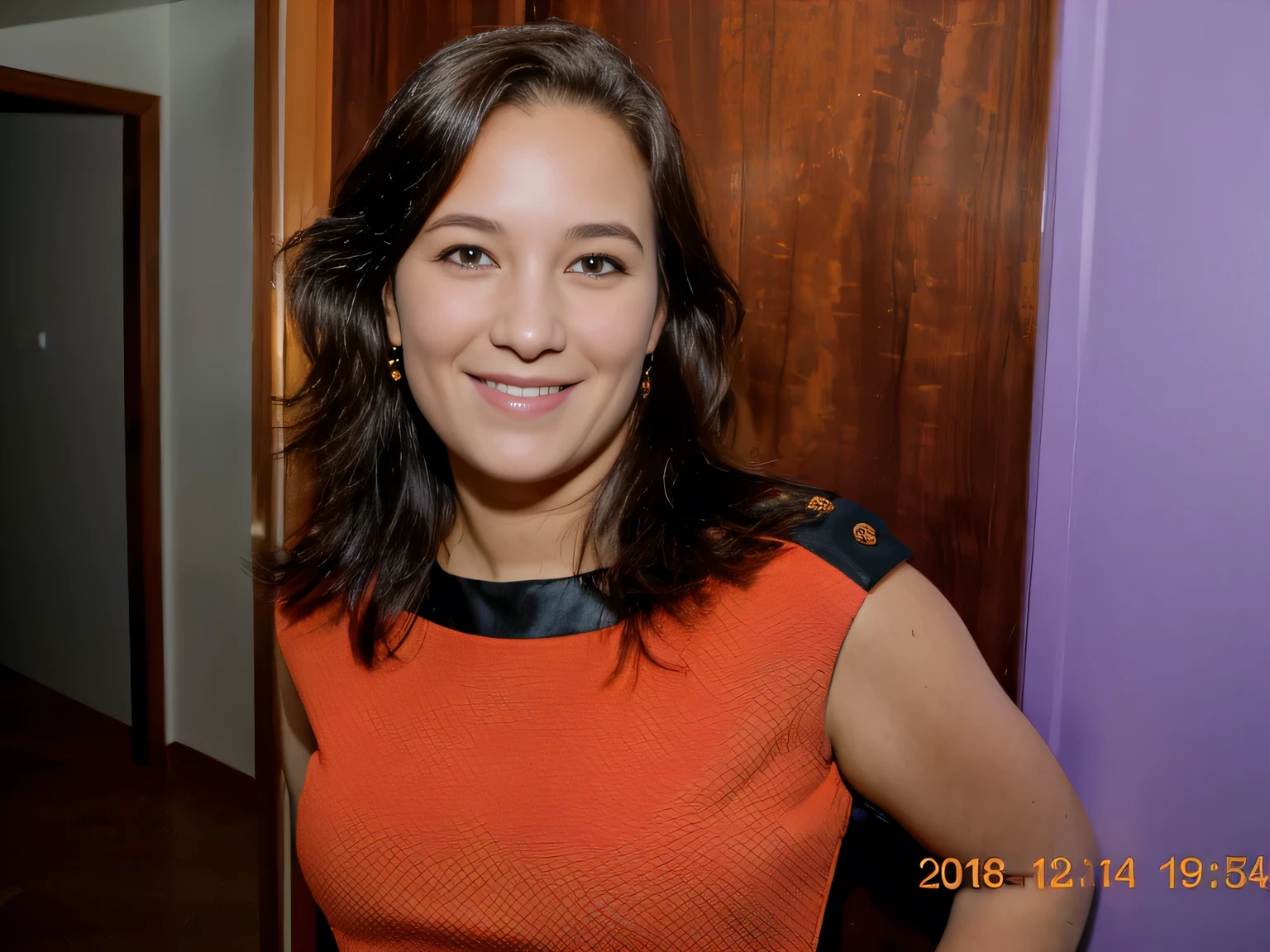 smiling woman in orange dress standing in front of a door 