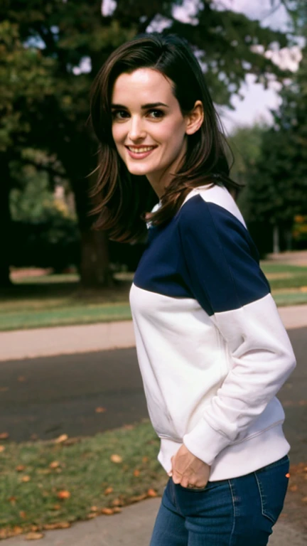 Winona Ryder dressed in a sweatshirt and jeans in a park and a sexy smile