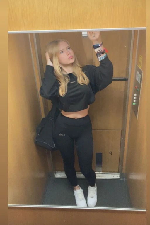 elevator, girl, black leggings, black shirt, blonde, crop top, big boobs, belly button showing, big tits