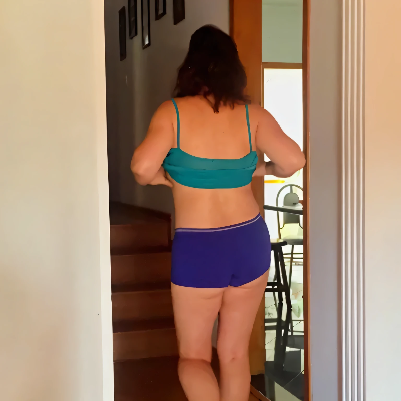 there is a woman in a blue bikini and purple shorts, view from the back, seen from the back, side view of her taking steps, shapely derriere, seen from behind, middle shot waist up, sport bra and dark blue shorts, in shorts, view from behind, looking outside, shot from the back, photographed from the back, waist - shot