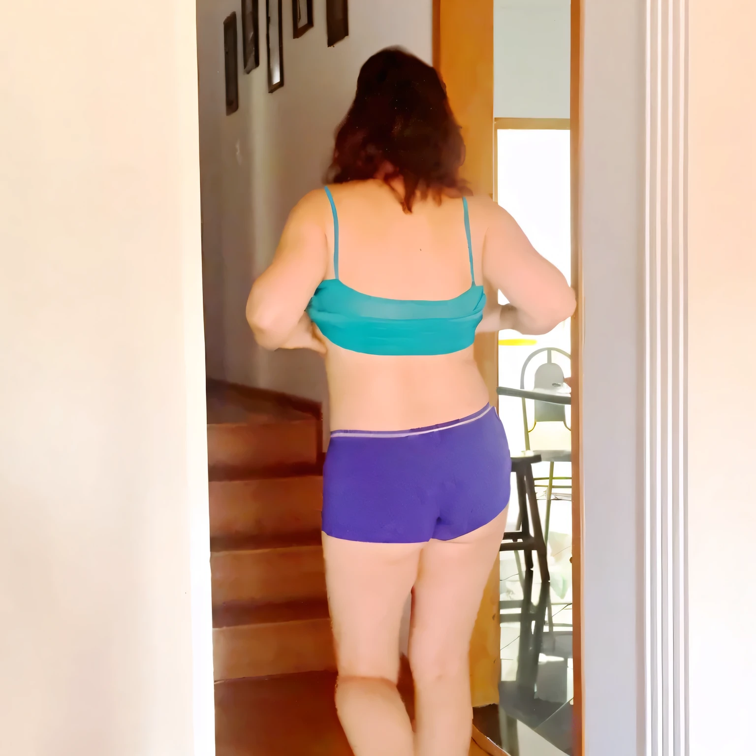 there is a woman in a blue bikini and purple shorts, view from the back, seen from the back, in shorts, seen from behind, wearing a camisole and shorts, middle shot waist up, waist - shot, looking outside, view from behind, backview, shot from the back, rear-shot, from the back, sport bra and dark blue shorts