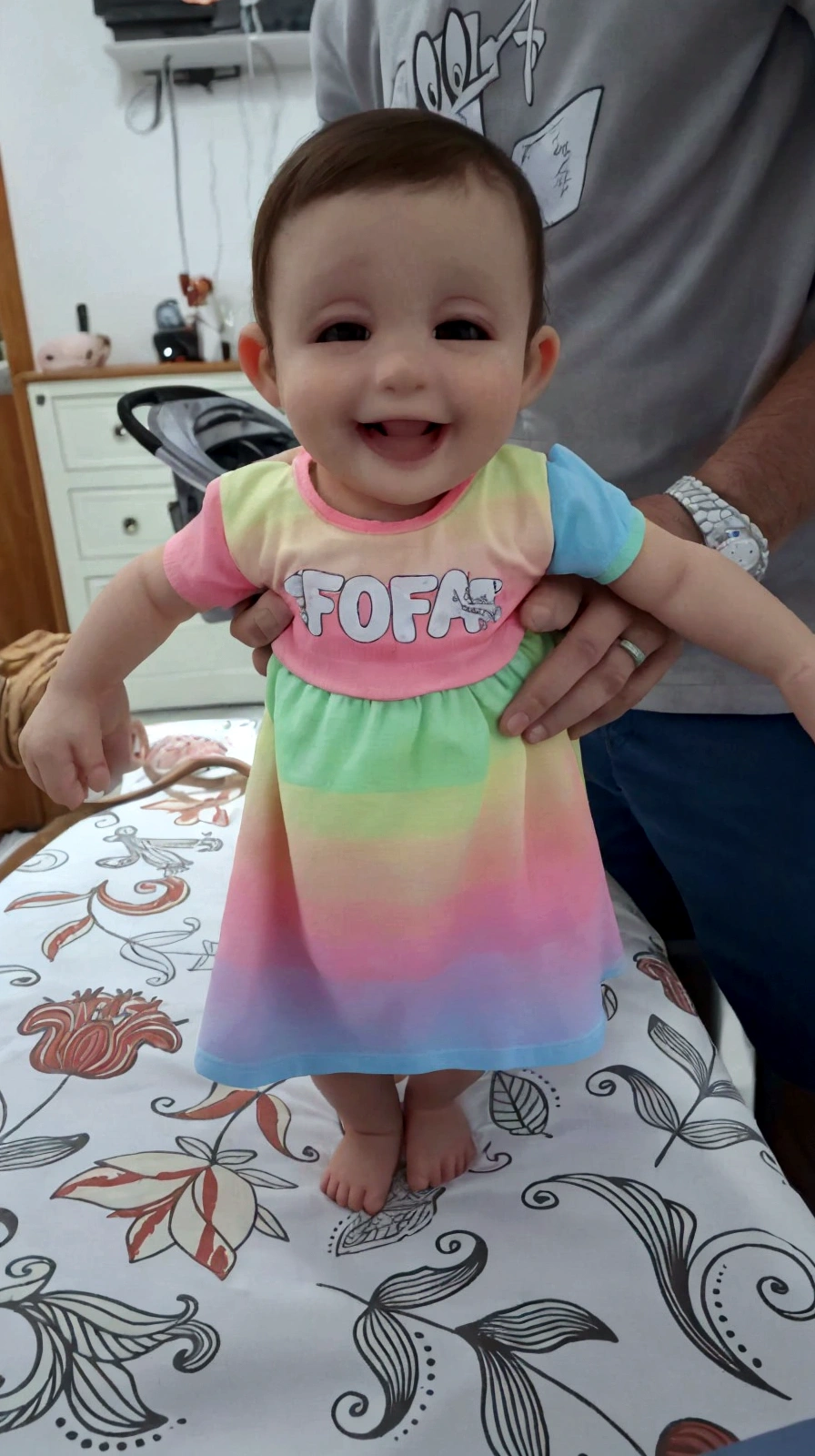 there is a baby that is on a table with a man, cute colorful adorable, she is smiling and excited, ela tem um rosto fofo e expressivo, she is smiling and happy, ela expressando alegria, ela tem um rosto fofo, sorria no rosto dela, 