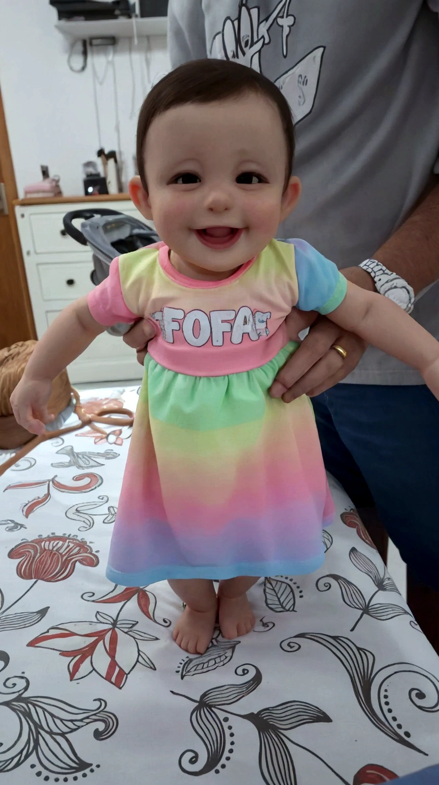 there is a baby that is on a table with a man, cute colorful adorable, she is smiling and excited, ela tem um rosto fofo e expressivo, she is smiling and happy, ela expressando alegria, ela tem um rosto fofo, sorria no rosto dela,