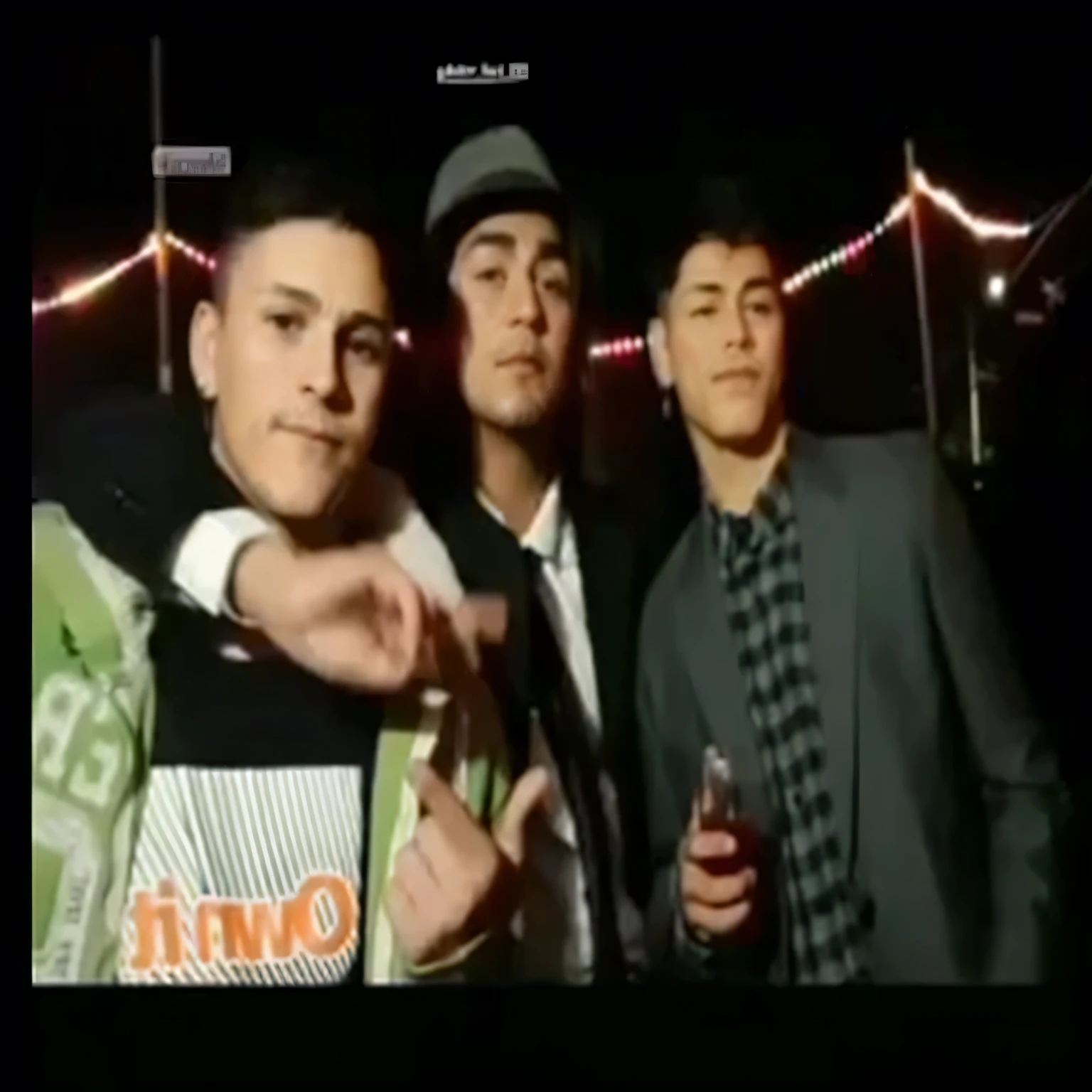 Hay tres hombres juntos en una room oscura., room, captura, chillin En el club together, Old images, still from a video musical, En el , low quality video, iphone videos, video musical, metraje nocturno, television images, dancing in el fondo, performing a video musical, suave en _ el fondo, metraje granulado